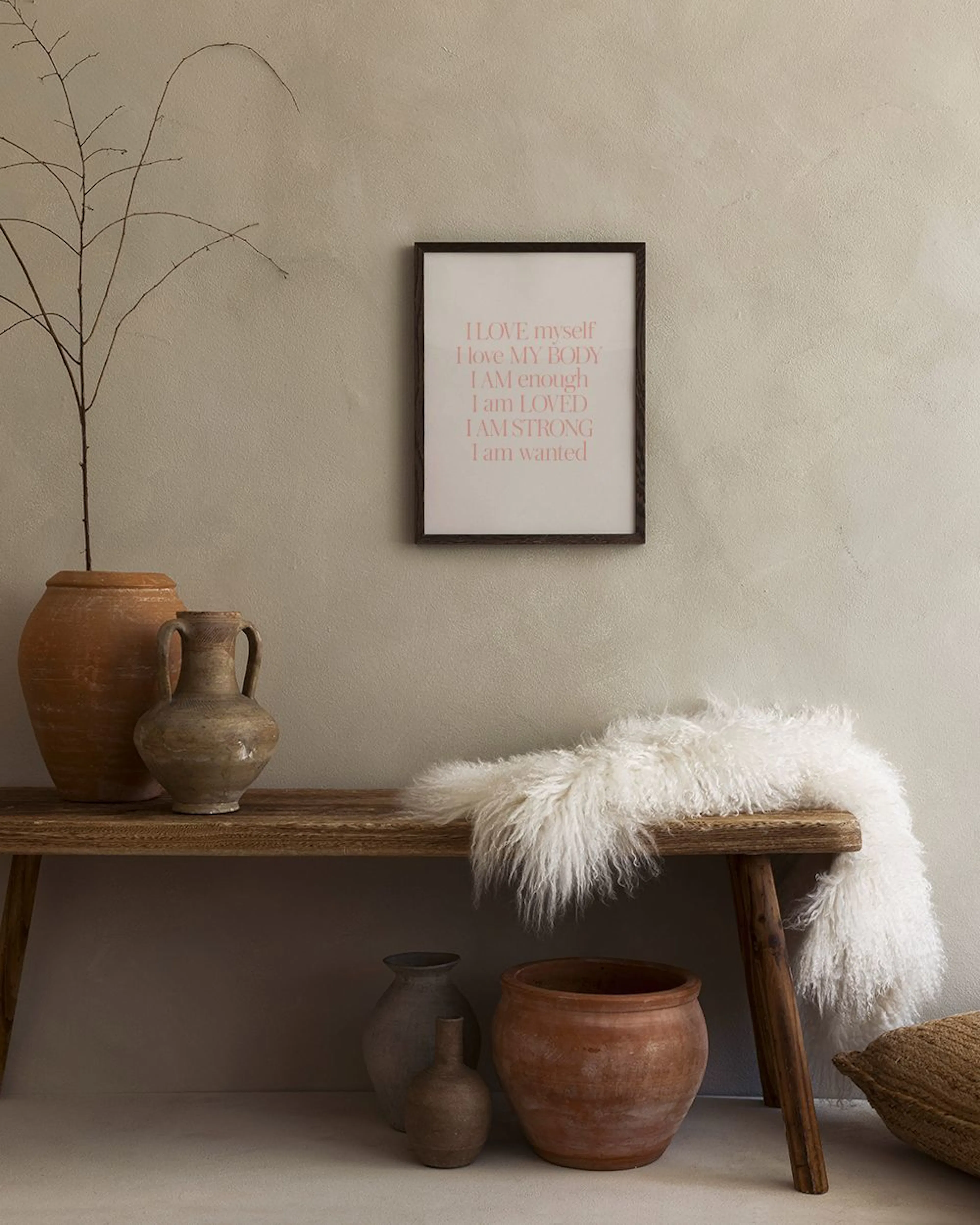 Poster mit positiven Affirmationen in Pink auf Weiß, über einem Sofa in einem modernen Wohnzimmer.