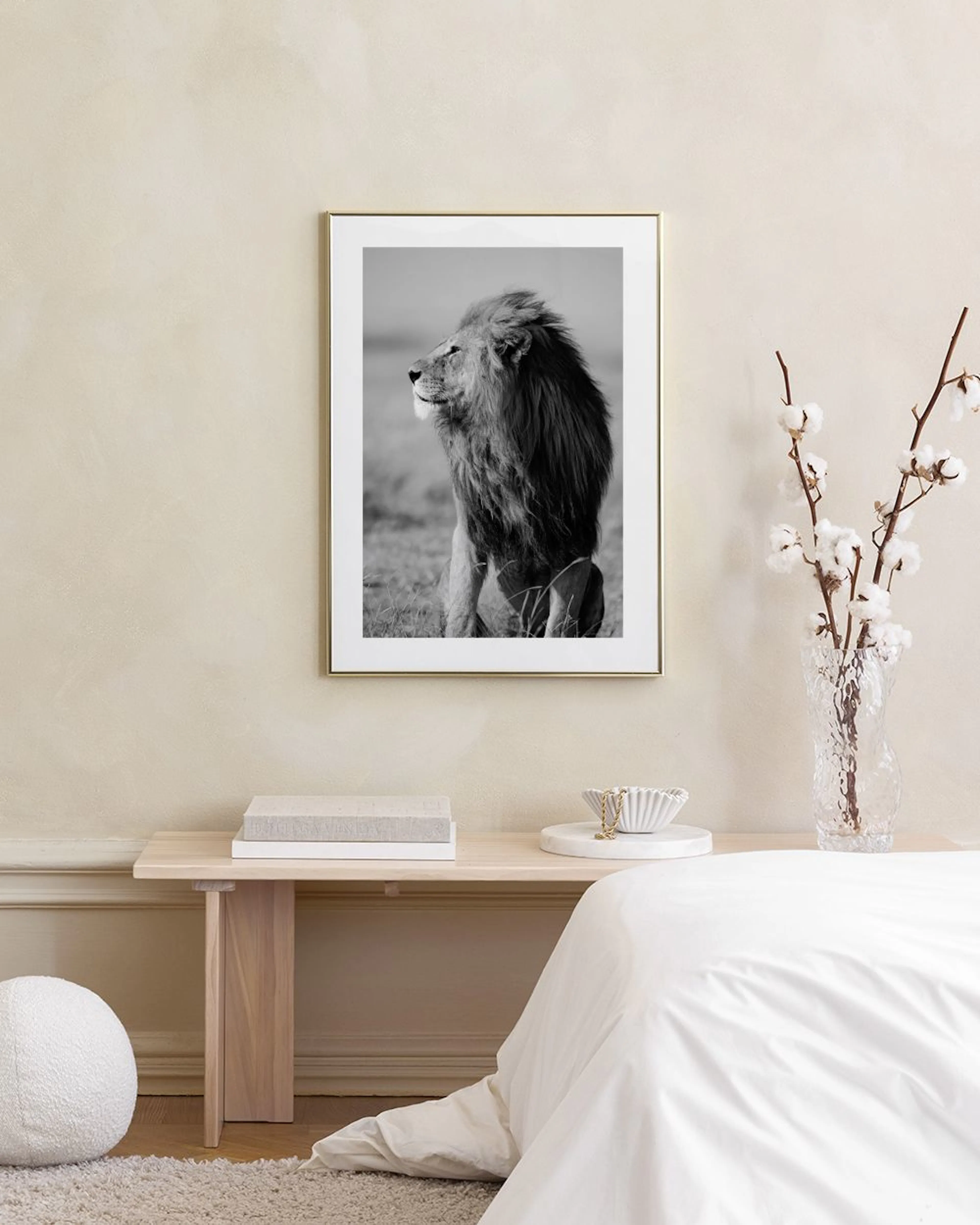 Black and white print of a majestic lion with a flowing mane, sitting in profile, displayed above a concrete bench.