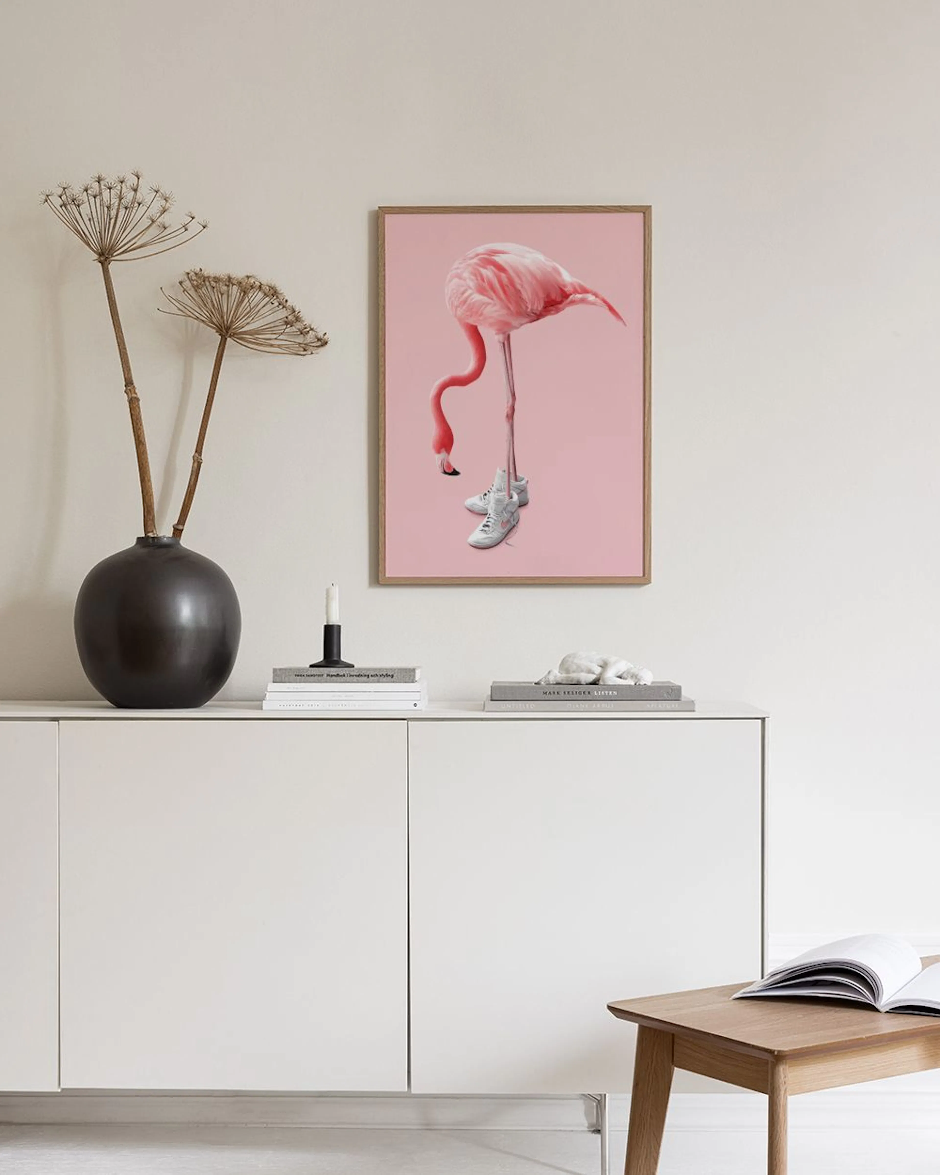 Affiche dun flamant rose portant des baskets blanches, sur fond rose. Elle est accrochée au-dessus dun meuble de rangement avec 