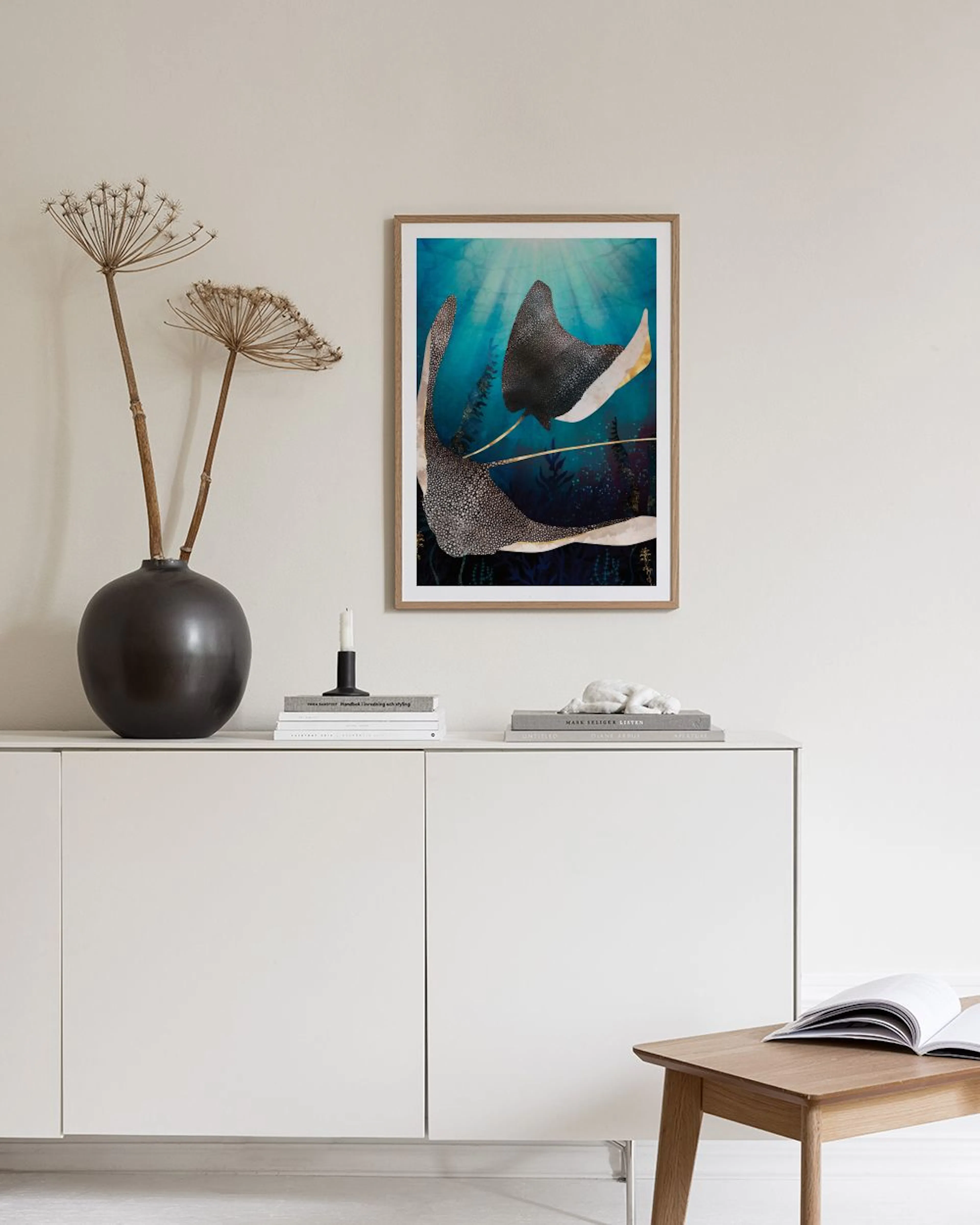 Poster van twee gevlekte adelaarsroggen onder water, met algen, op een betonnen bankje met lamp.