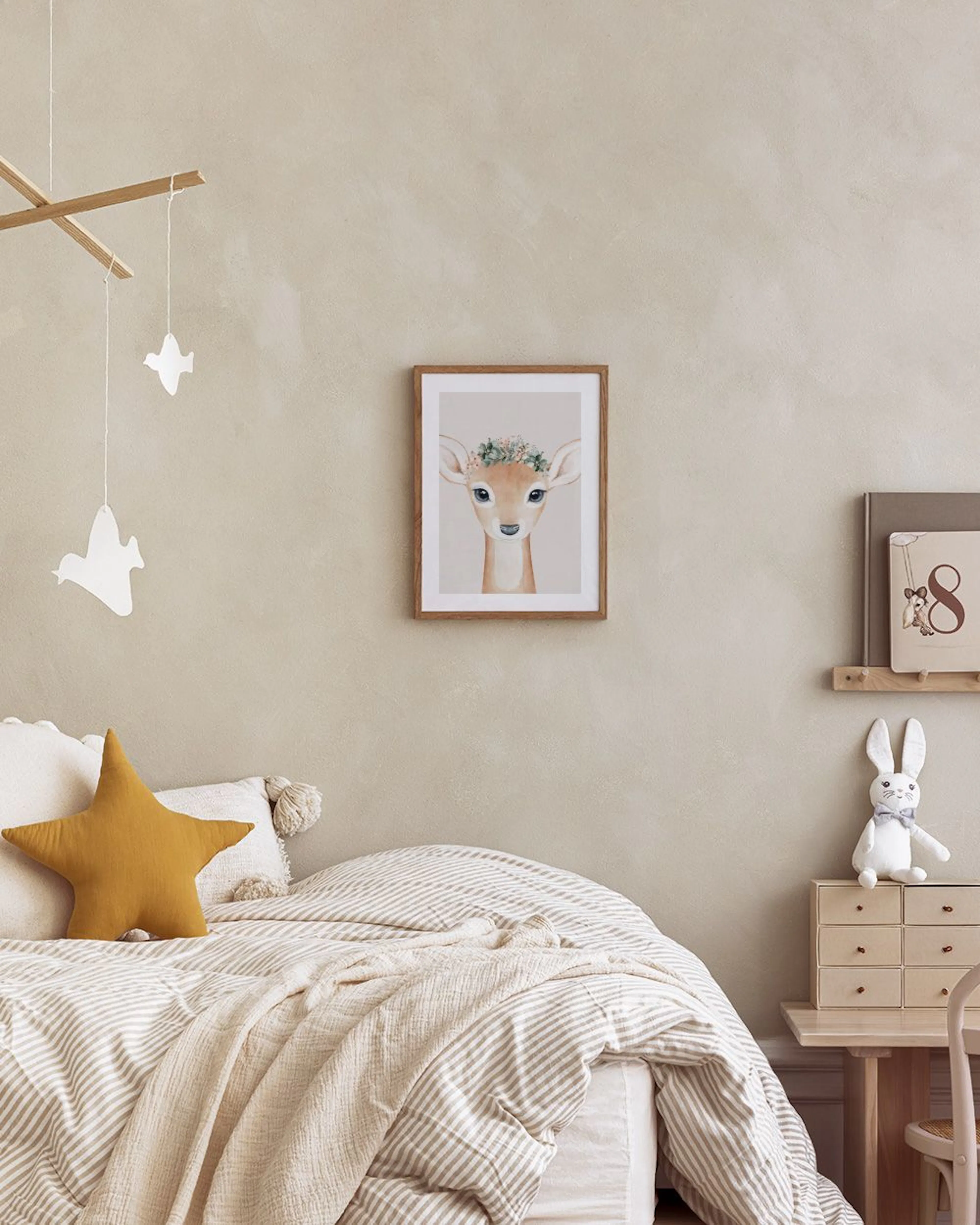 Póster de un cervatillo con corona de flores, en una habitación de niños sobre una mesita de noche junto a instrumentos musicale