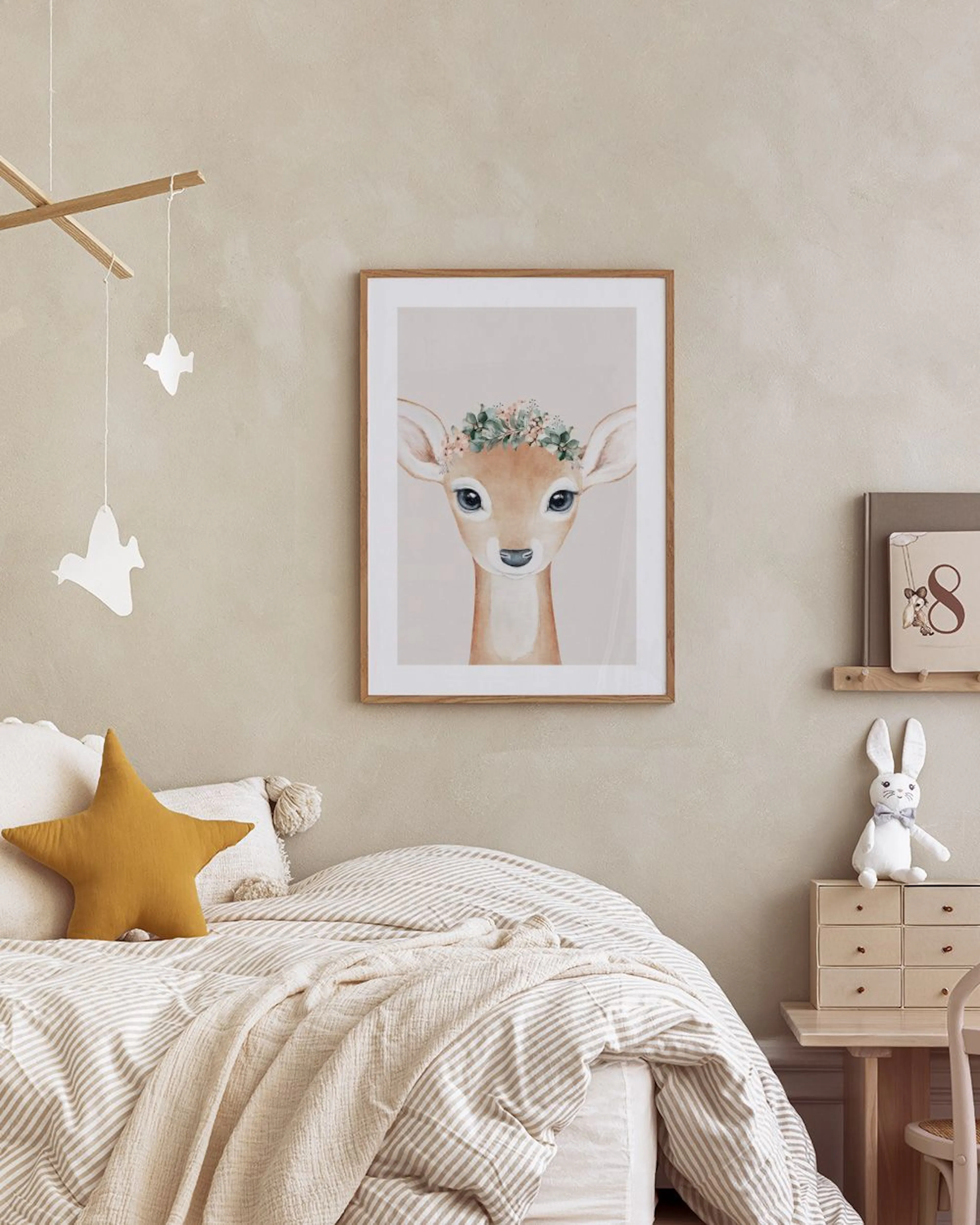 Affiche enfantine dun faon aux grands yeux bleus avec une couronne florale, affichée dans une chambre.