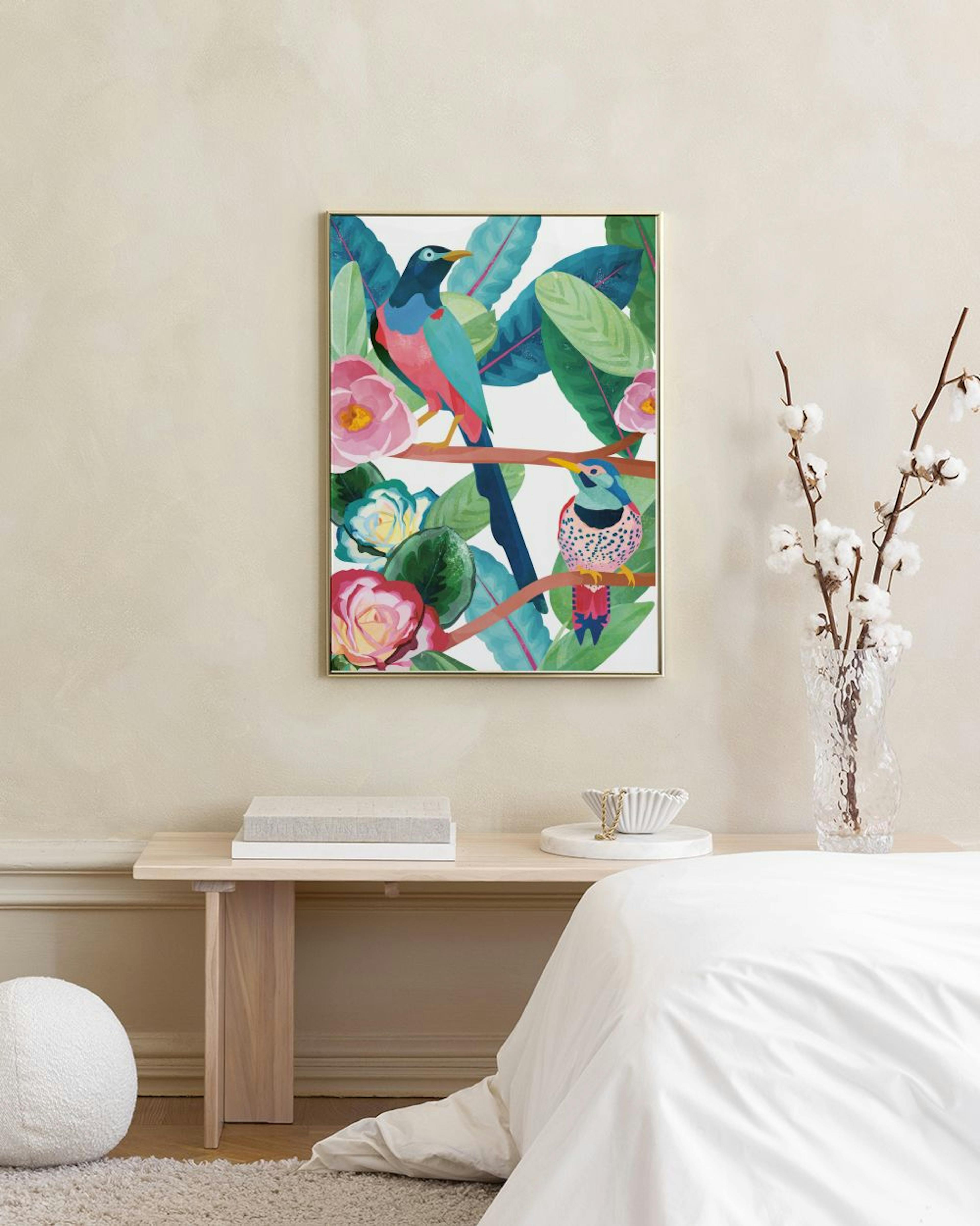 Poster mit zwei bunten Vögeln auf einem Ast, umgeben von grünen Blättern und rosa Blüten, über einem weißen Sideboard mit Vasen.