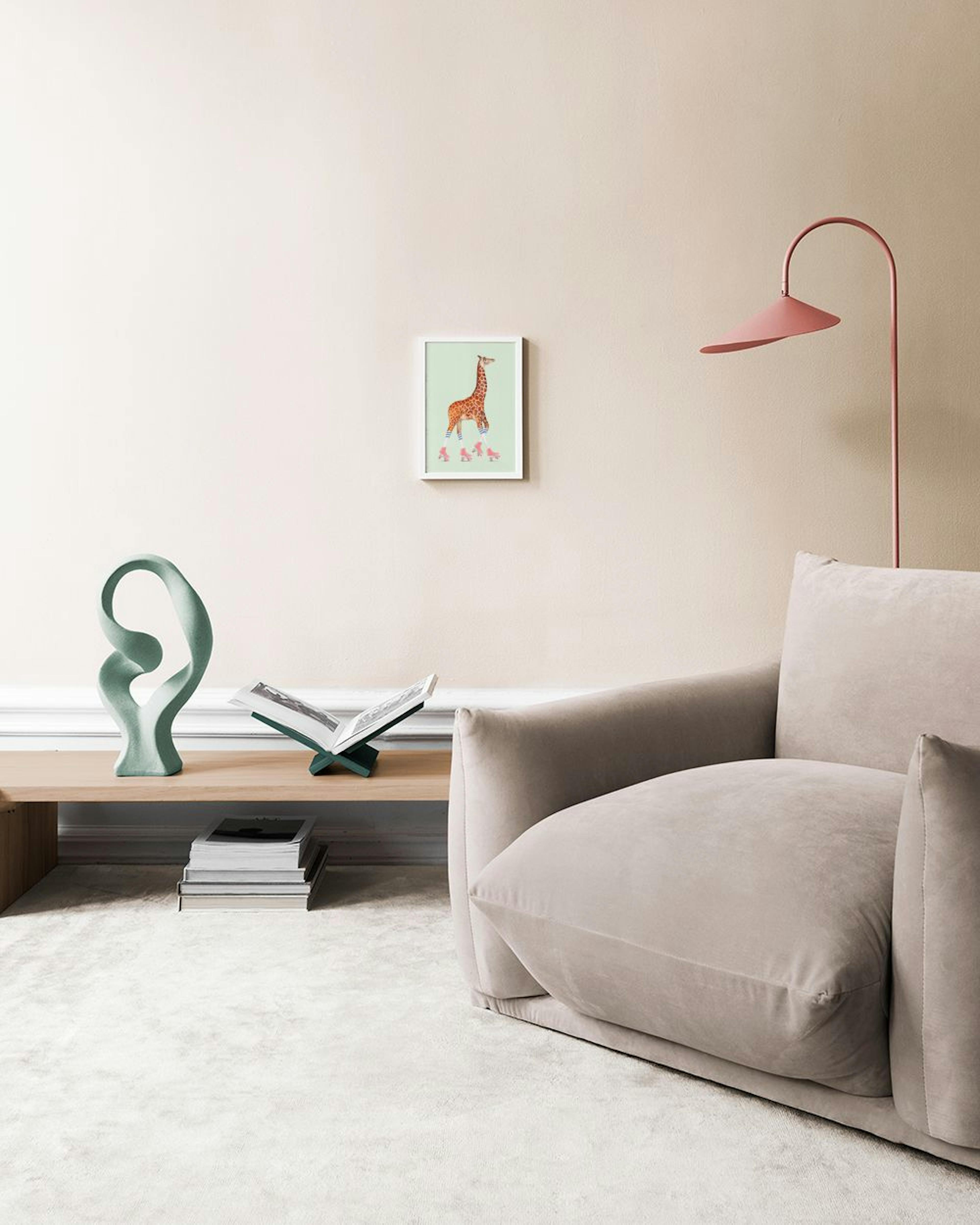 Poster mit einer Giraffe auf Rollschuhen vor hellgrünem Hintergrund, über einem Holztisch mit Büchern und Laptop.