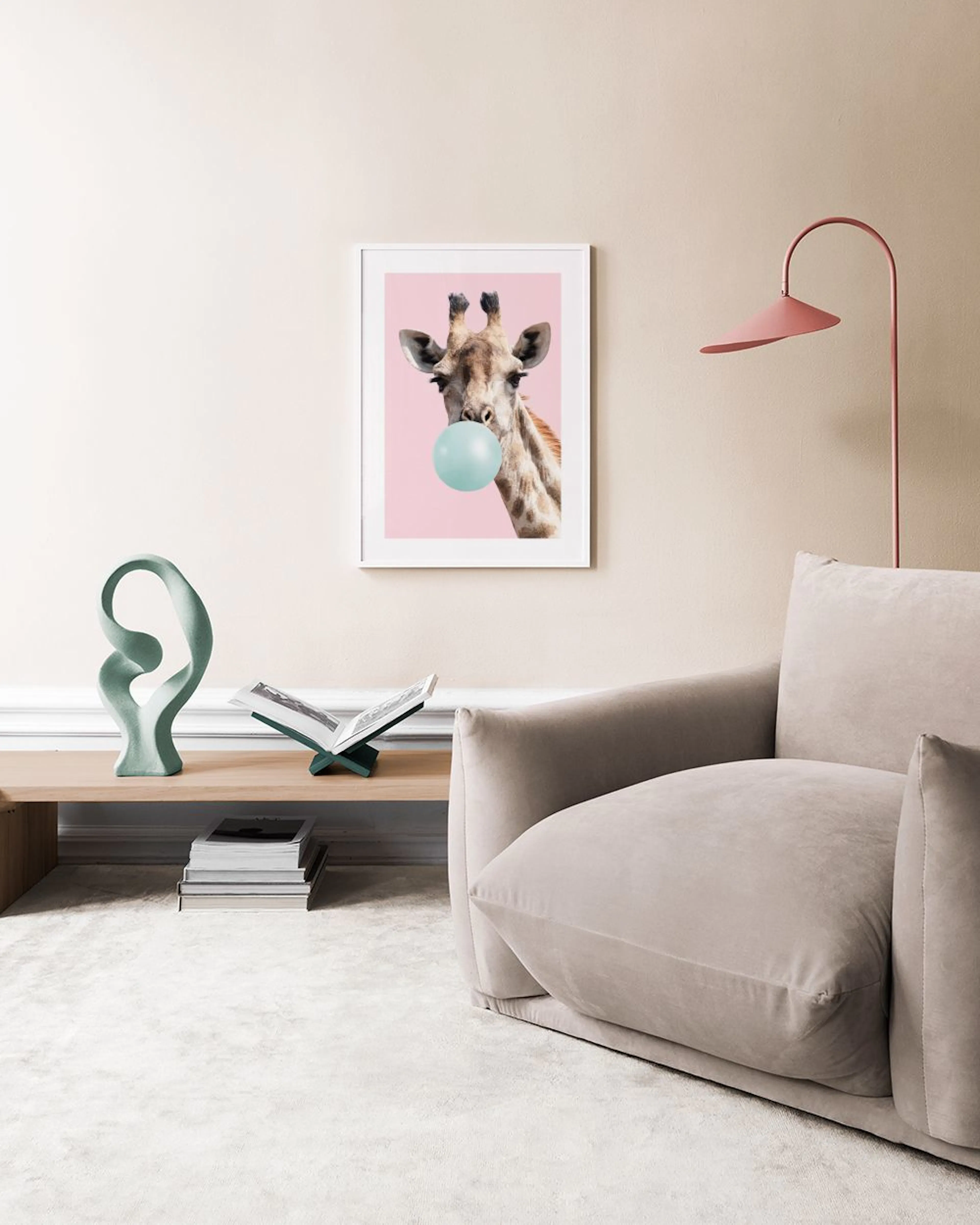 A fun giraffe print with a blue bubblegum bubble, displayed above a wooden desk with books in a bright room.