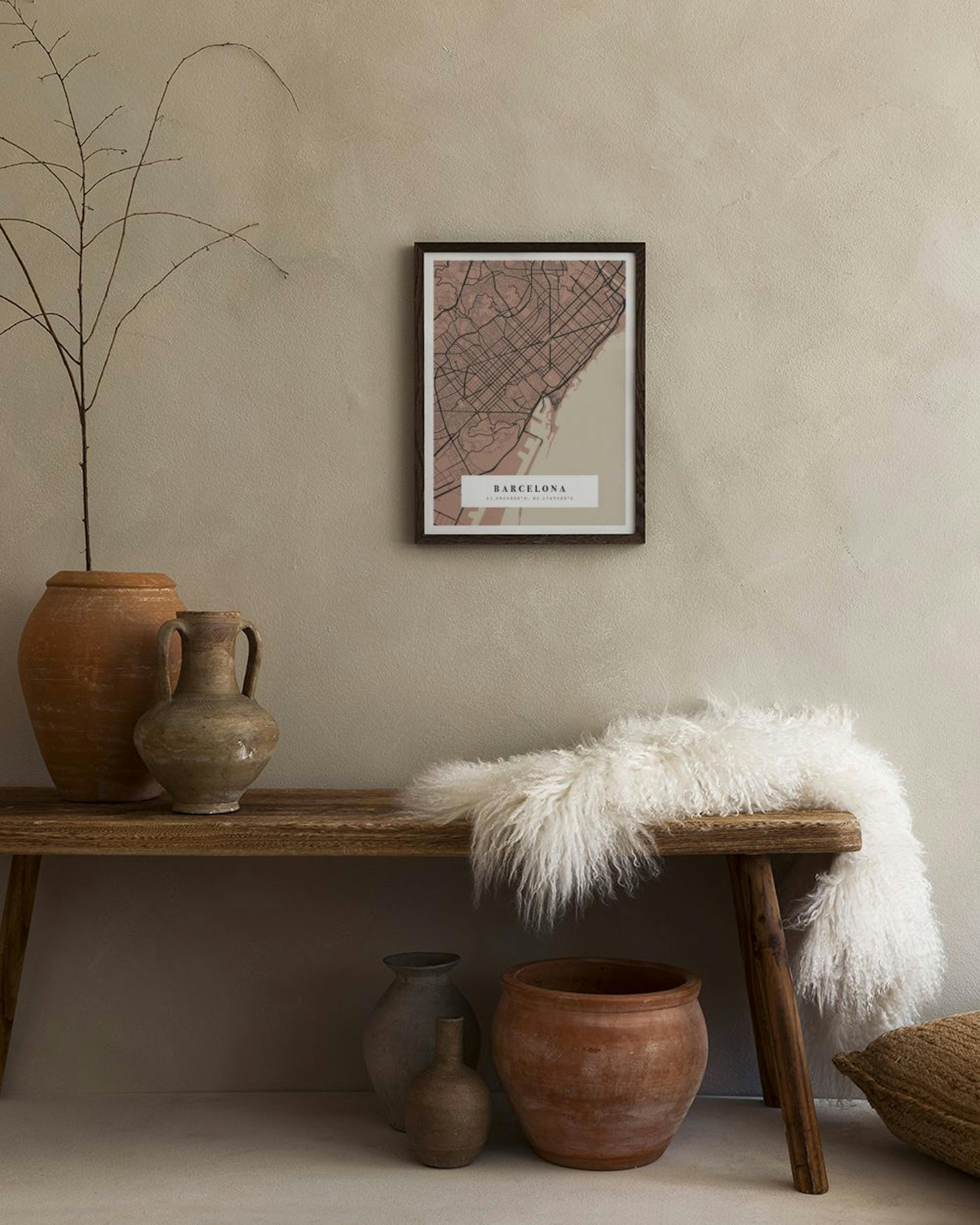 Plakat personalizowany z mapą Barcelony w odcieniach różu, beżu i brązu, zawieszony nad białą komodą z wazonami.