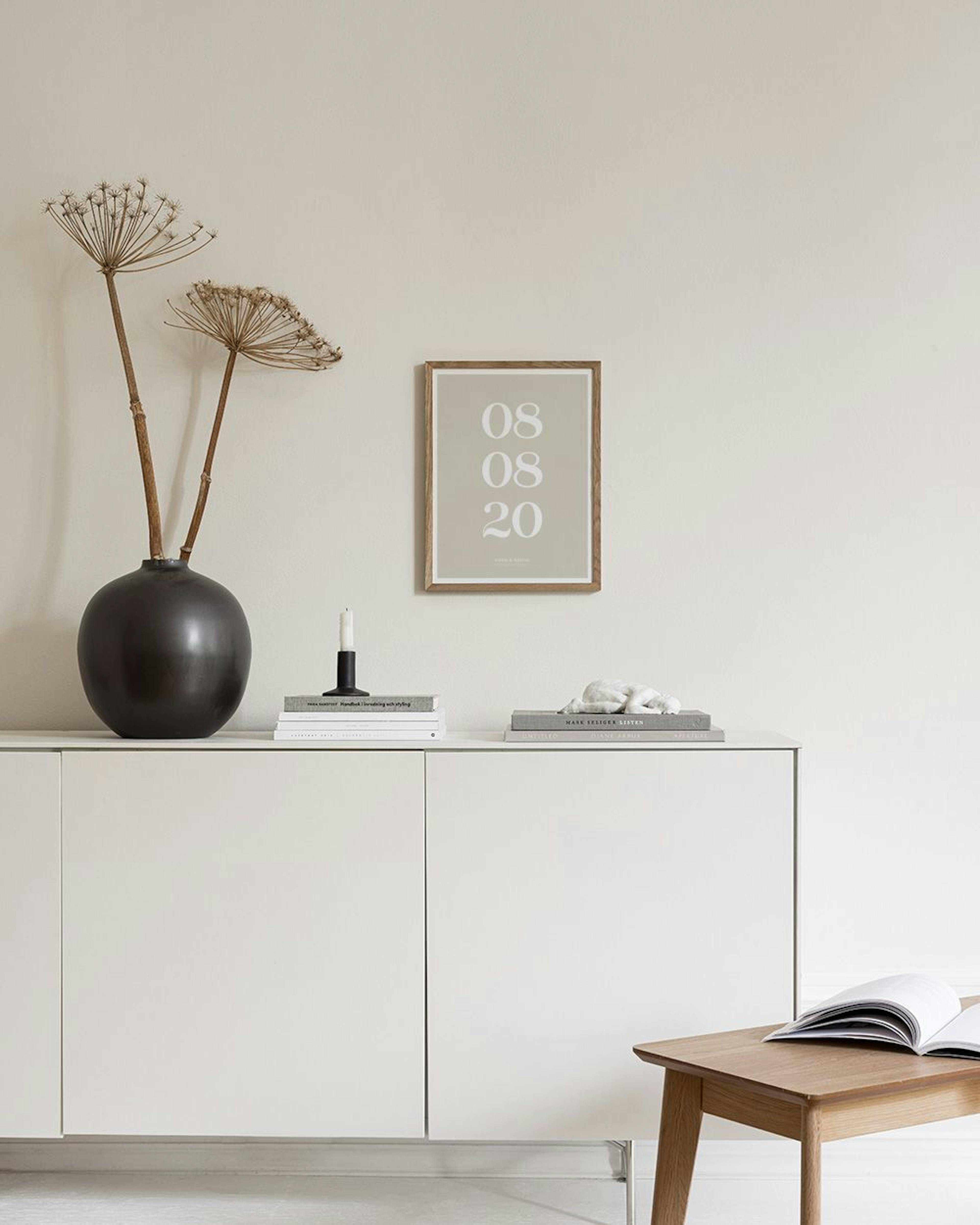 Affiche personnalisée avec une date et des prénoms sur fond beige, accrochée dans une pièce aux tons clairs au-dessus dun meuble