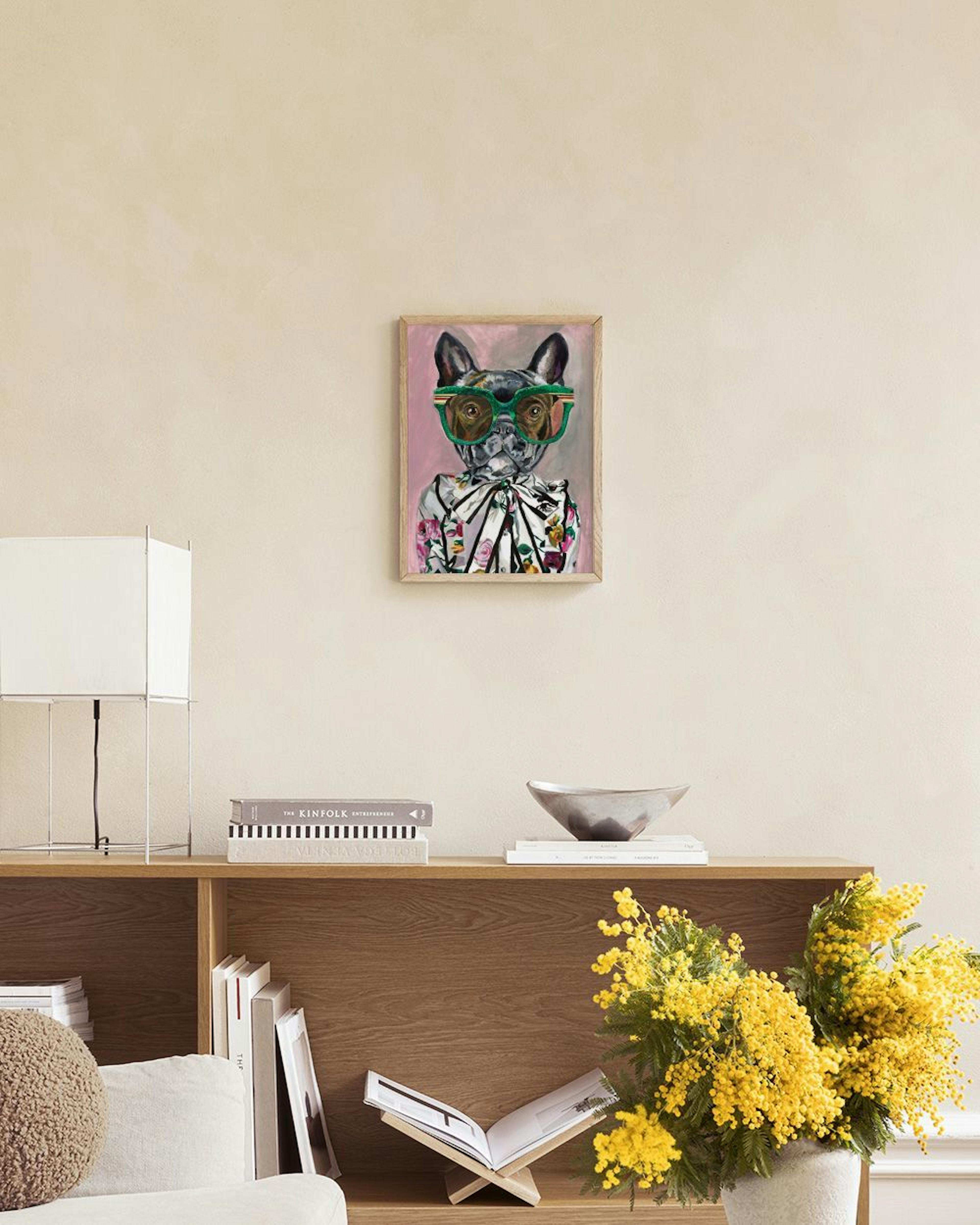 Plakat med en fransk bulldog i grønne solbriller og blomstret skjorte, hængende over en lyserød sofa med gul pude og hvid plaid.