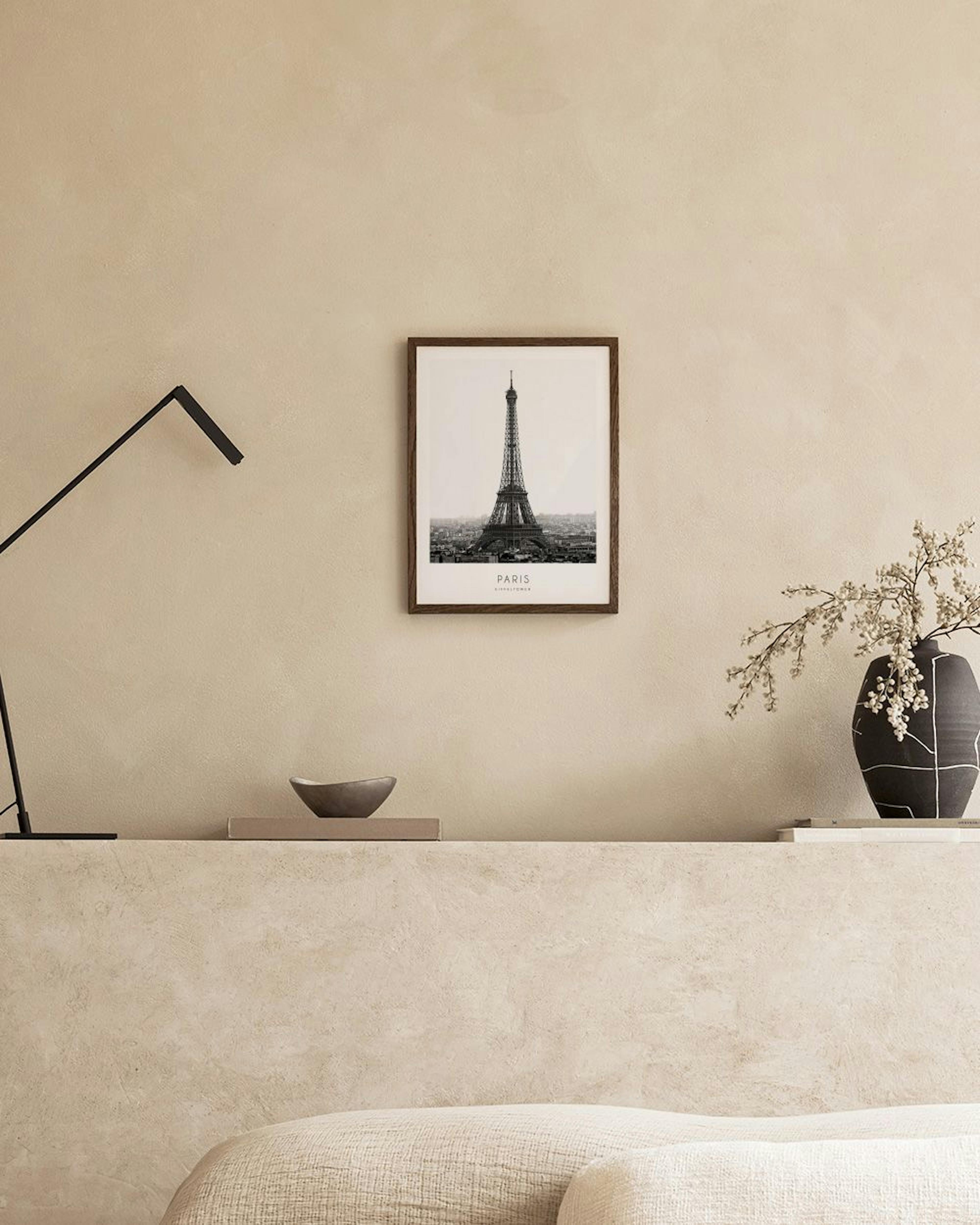 A black and white print of the Eiffel Tower and Paris cityscape, displayed on a white surface with gold candlesticks and a Monst