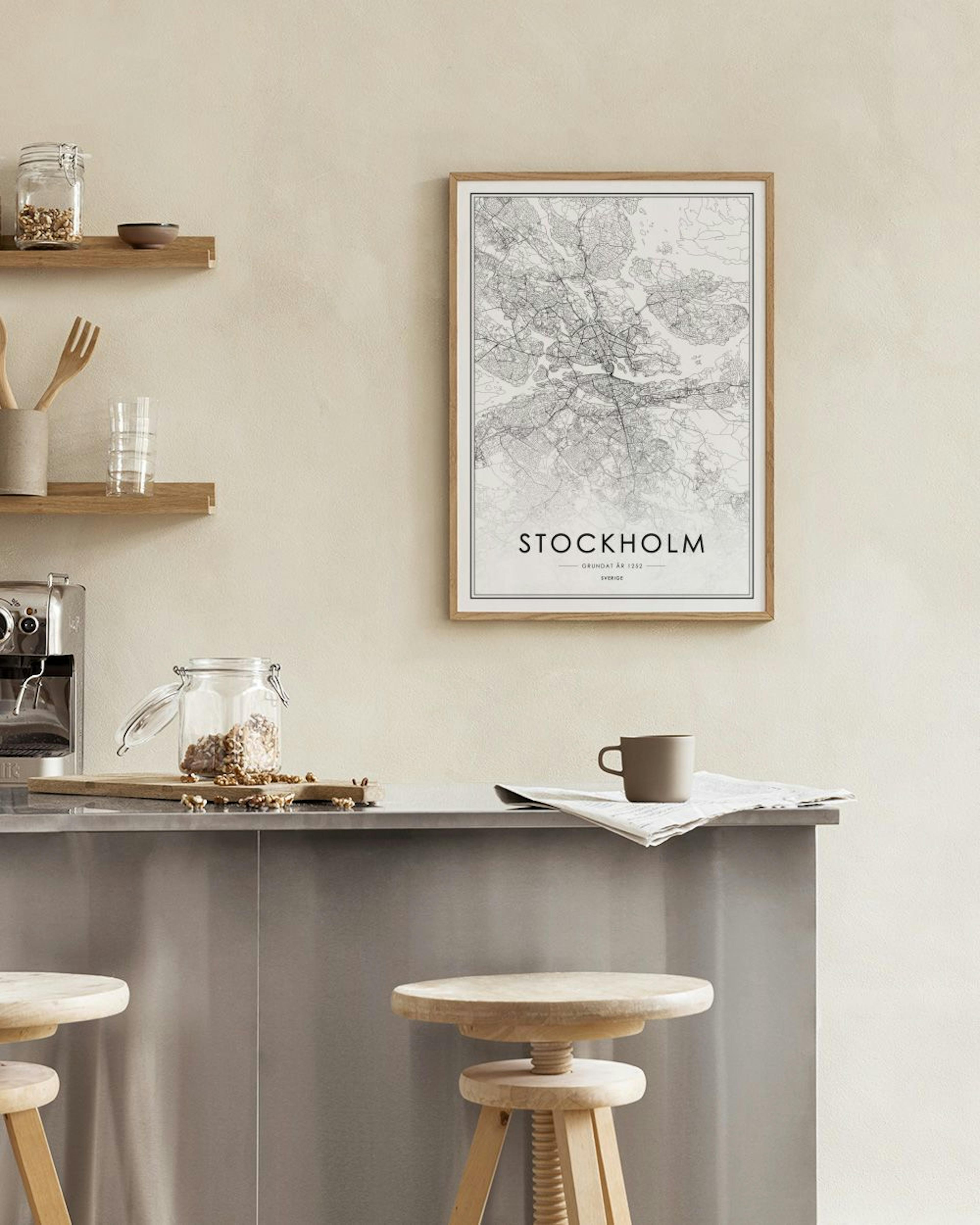 Plakát s mapou Stockholmu v černém rámu visí na šedé stěně nad modrým taburetem a černým stolkem s bílou vázou.