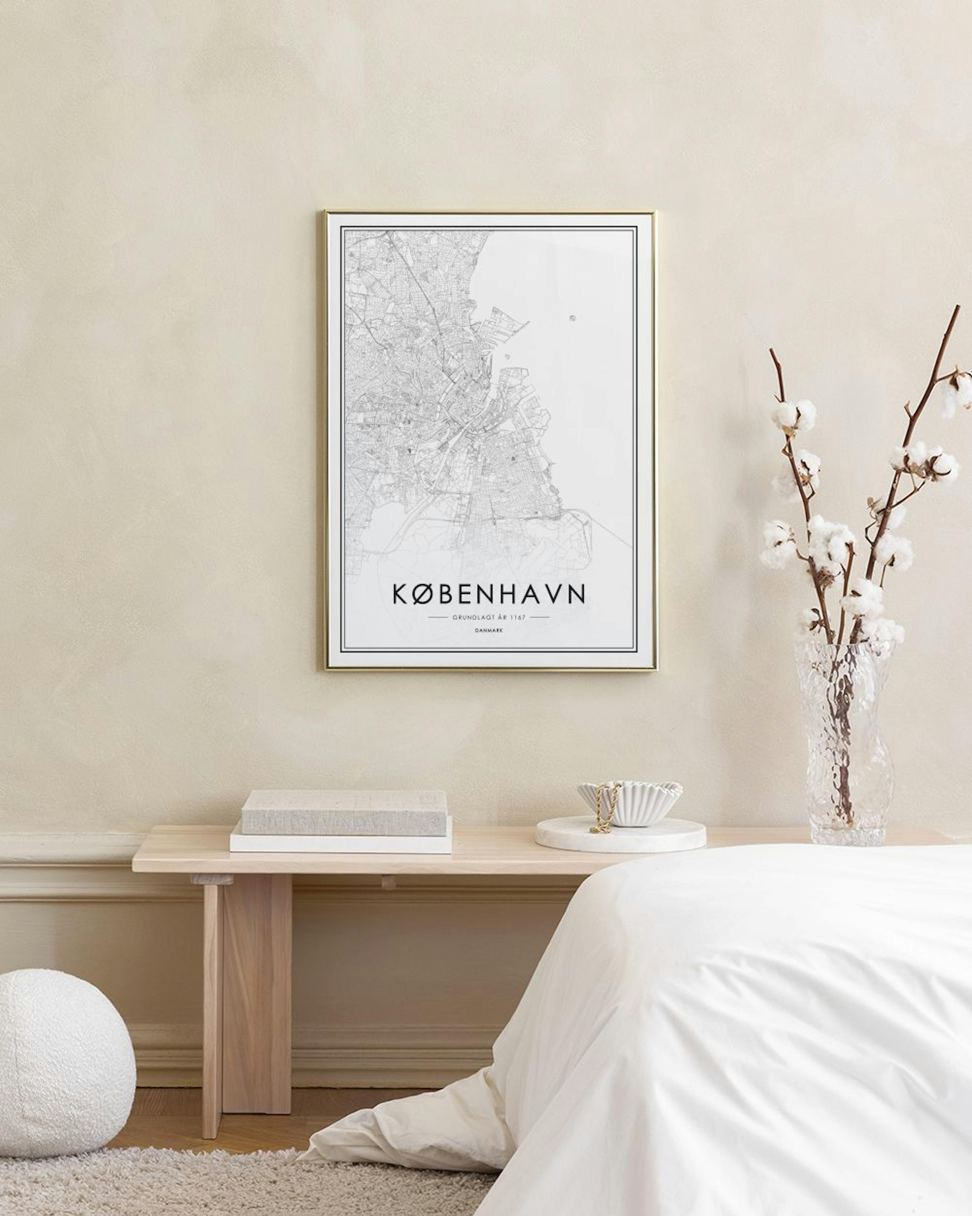 Poster de mapa de Copenhaga em preto e branco, com um cato e um castiçal dourado sobre uma superfície branca.