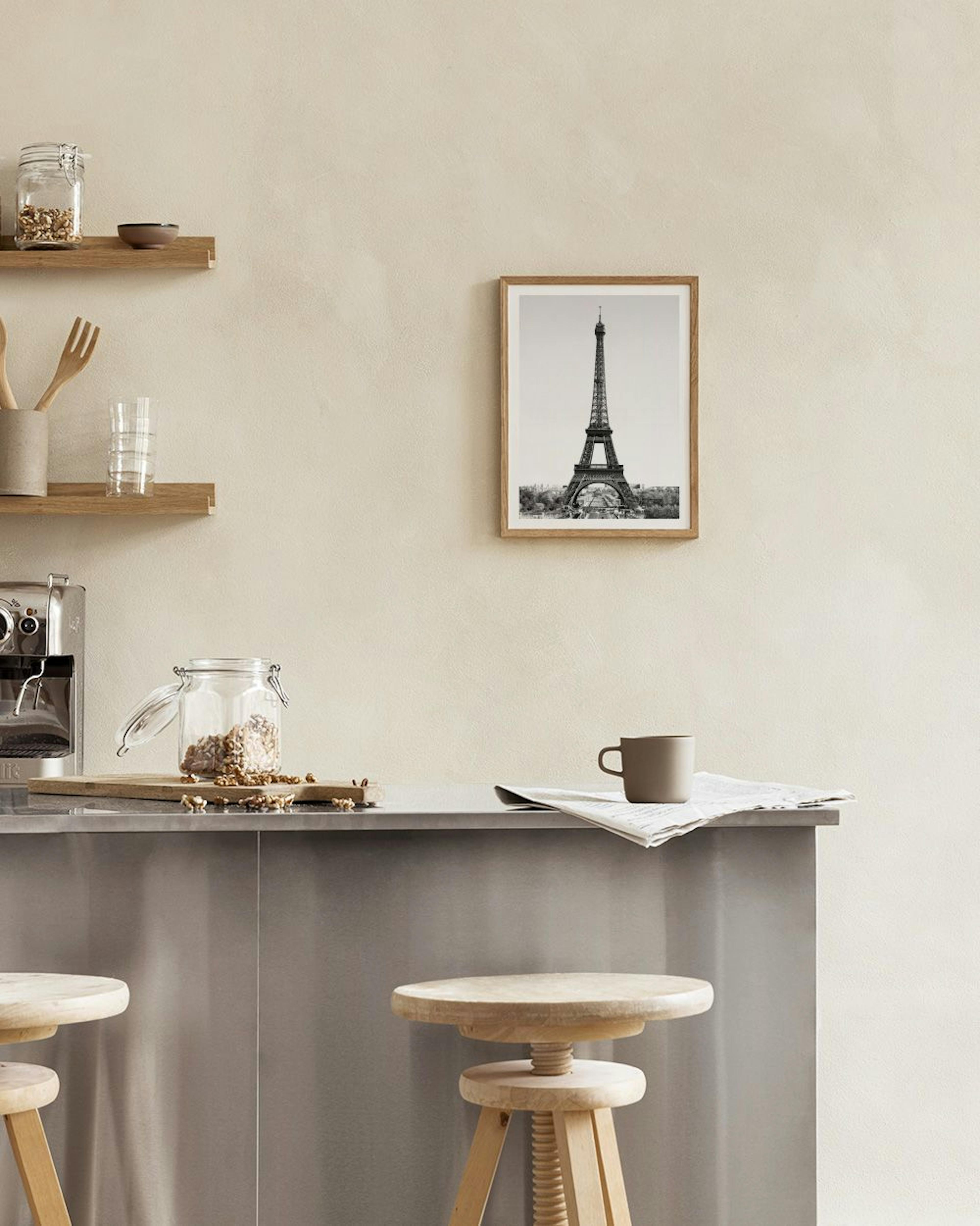 Poster con Torre Eiffel in bianco e nero, appoggiato su una scrivania bianca con lampada e oggetti decorativi.