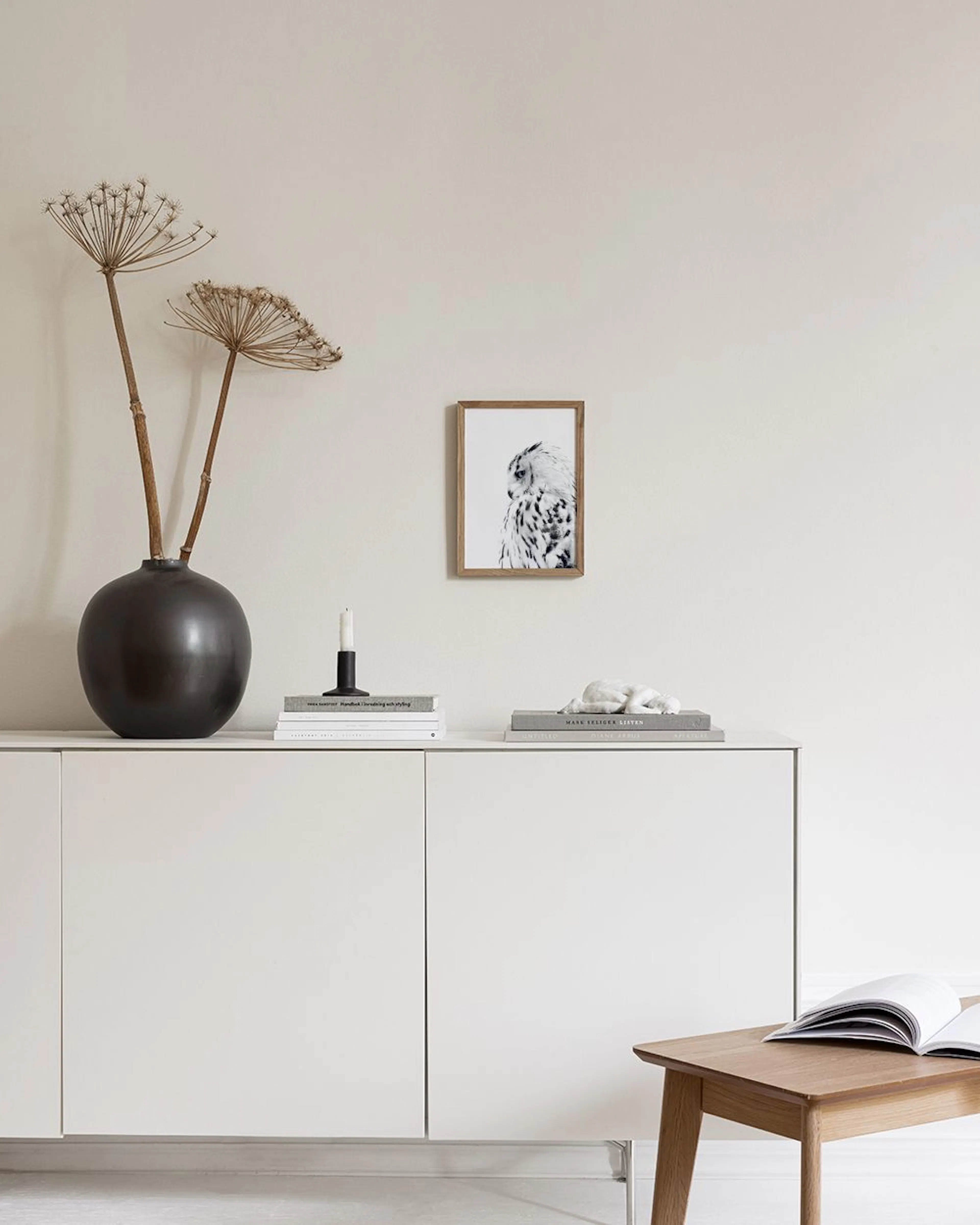 Poster con gufo bianco e nero, appeso in una camera da letto minimalista con sedia e vasi.