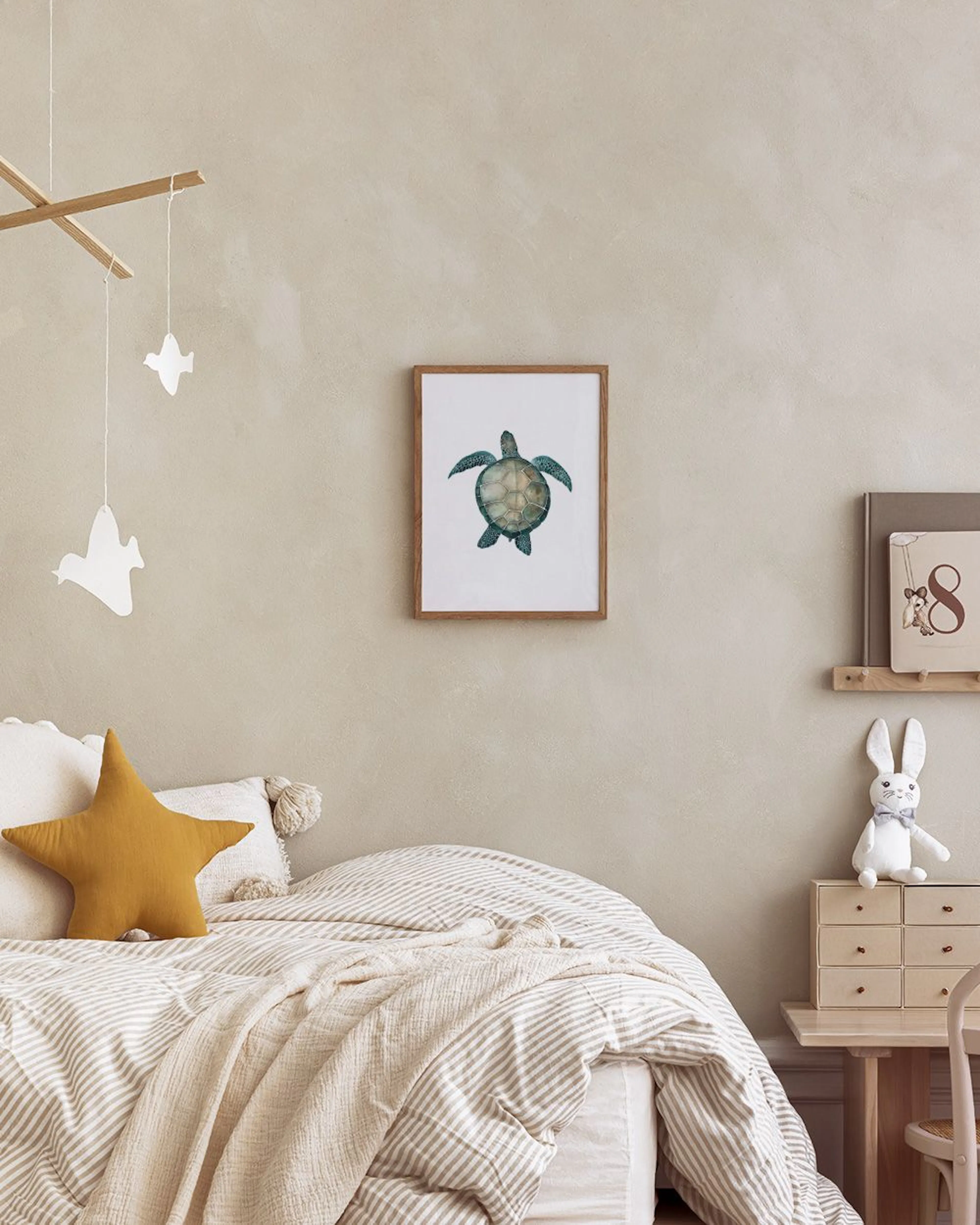 Poster mit einer grünen Meeresschildkröte, auf einem weißen Tisch mit goldenen Teelichthaltern und weißen Dosen.