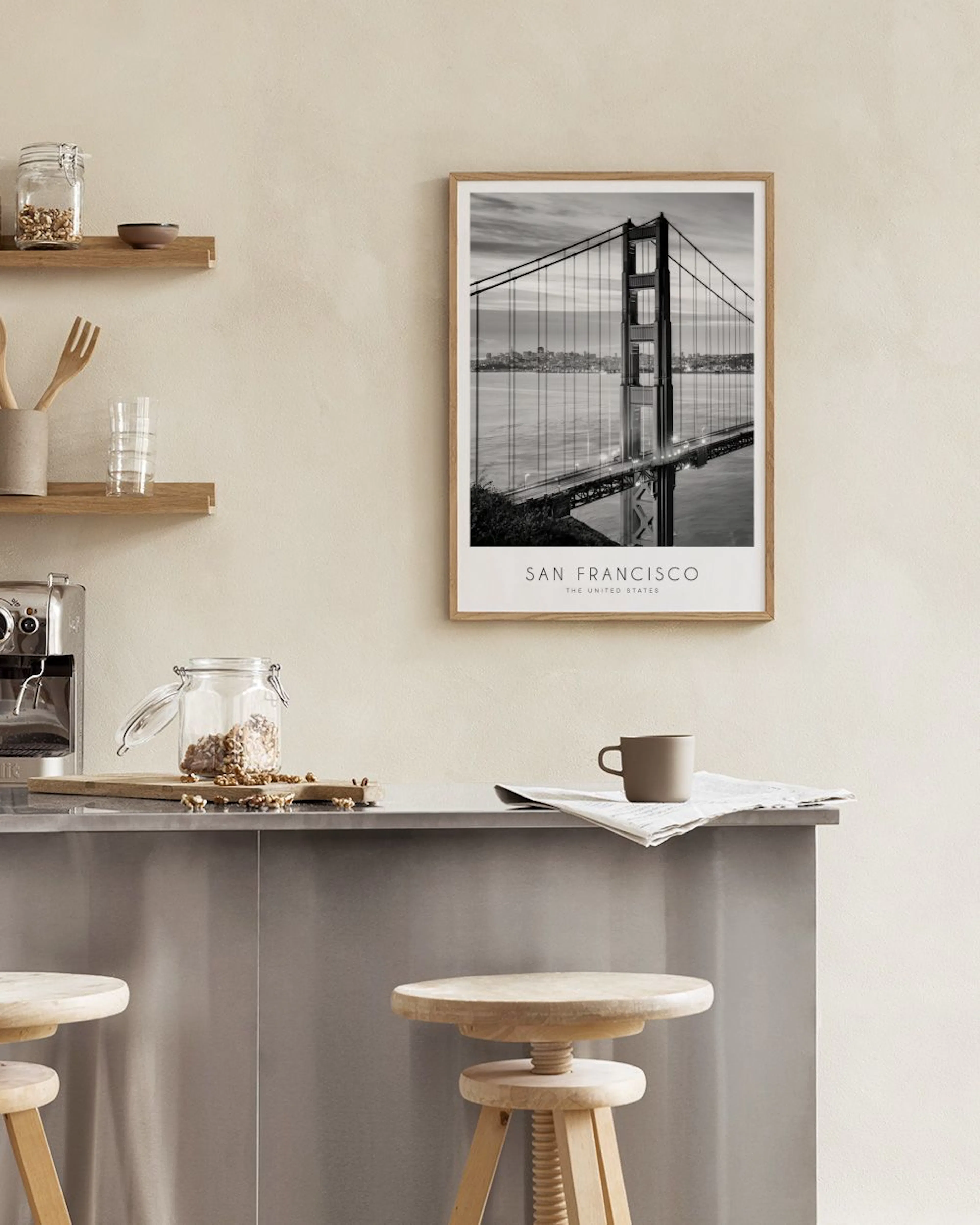 Schwarz-weiß Poster der Golden Gate Bridge in San Francisco, aufgehängt über einem Regal mit Büchern und Dekoration.
