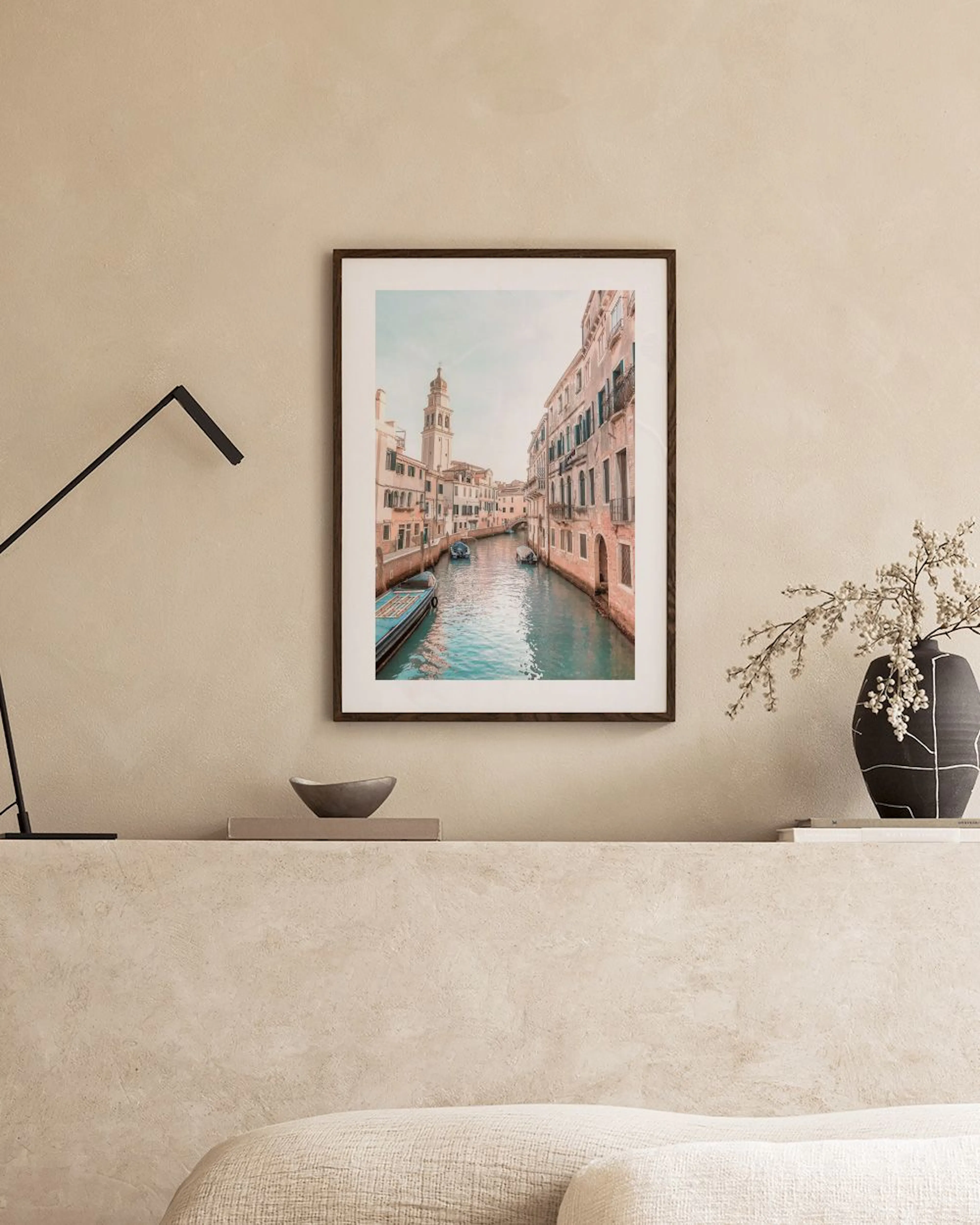 Affiche de Venise avec son canal et ses bâtiments, suspendue au-dessus dun fauteuil sarcelle avec un coussin blanc.