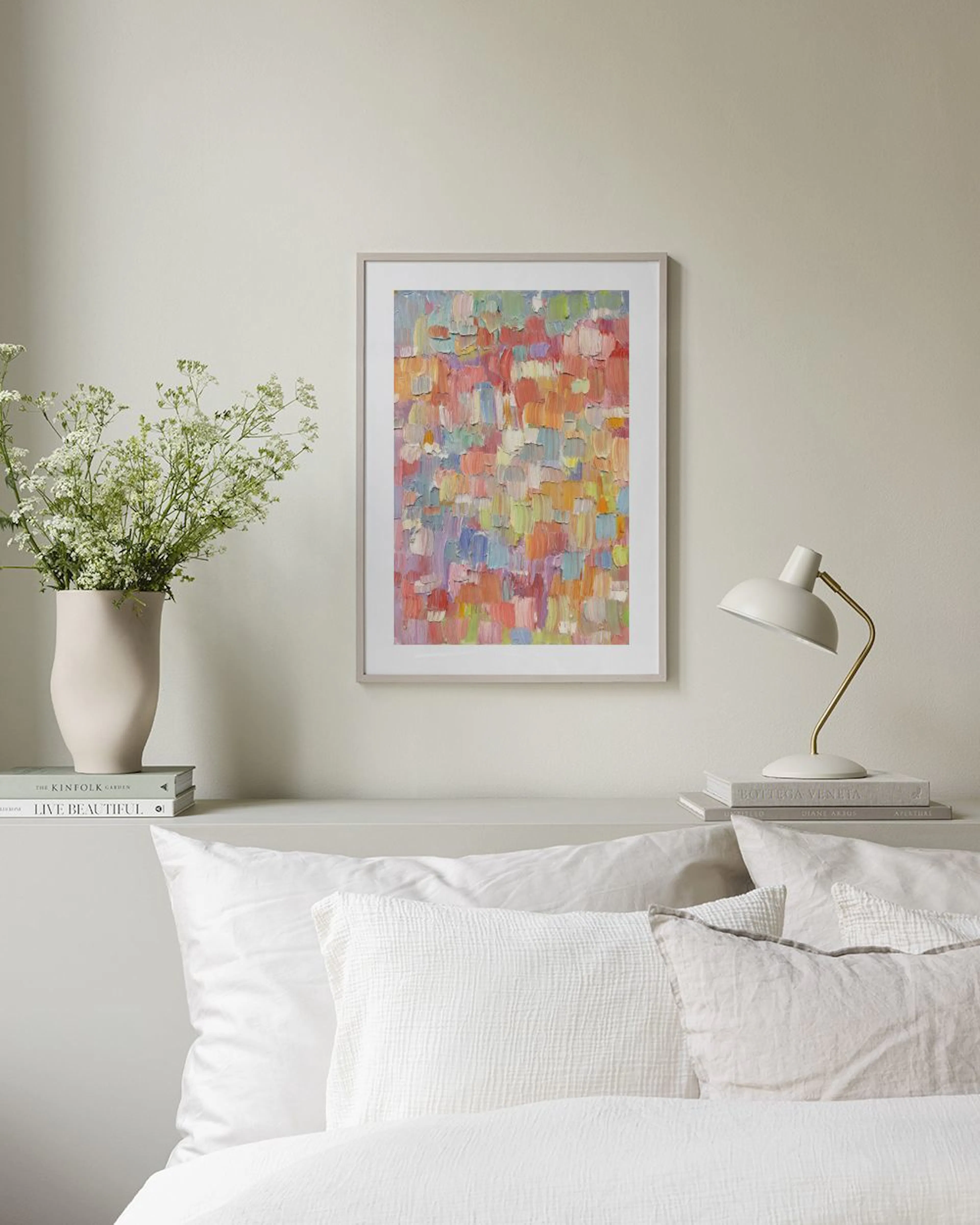 Poster met abstracte, kleurrijke verfstreken in pastelkleuren, hangend boven een roze bank met een deken en kussen.