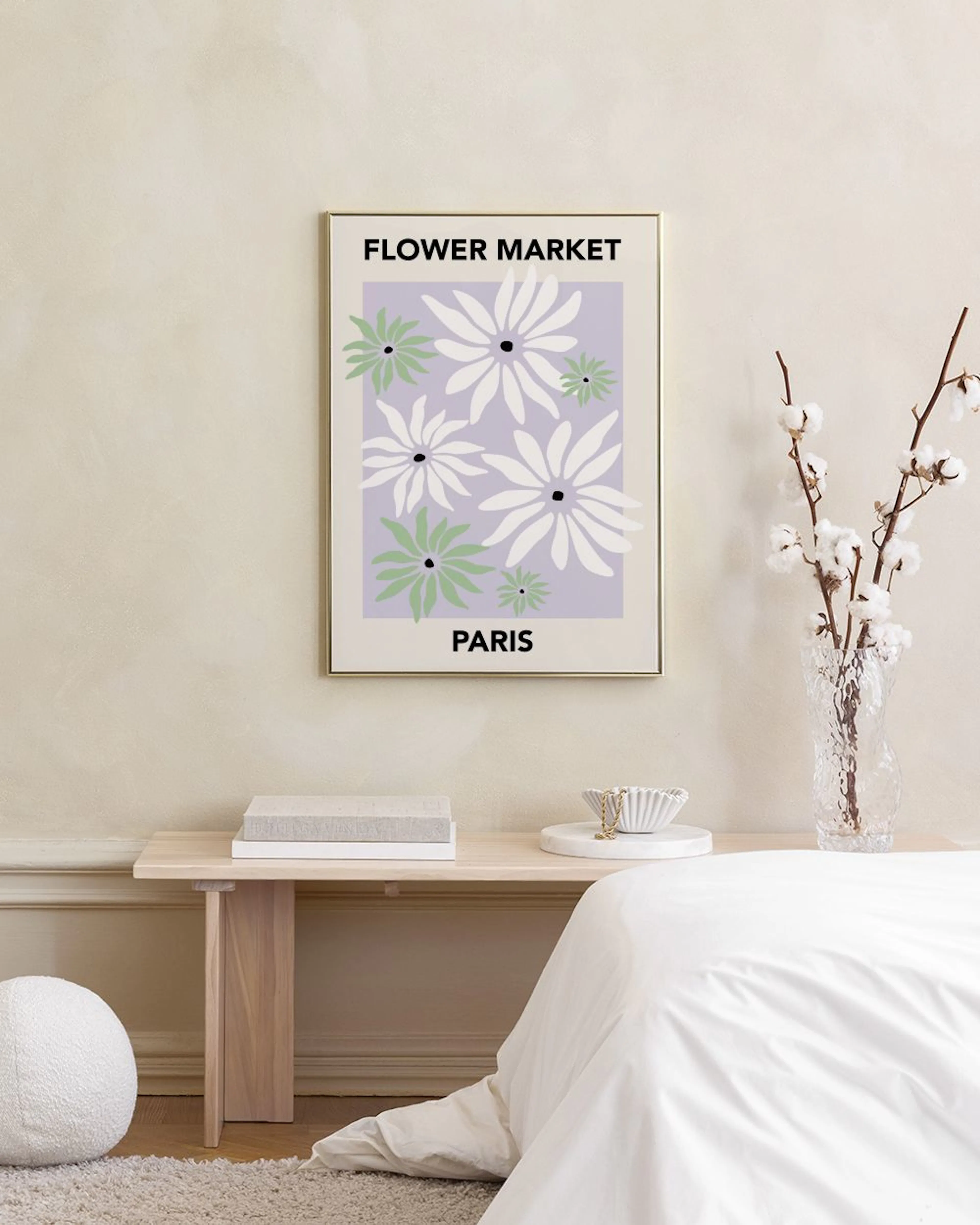 Póster Flower Market Paris con flores blancas y verdes sobre un fondo lila, colgado sobre un sofá verde claro con un cojín lila.