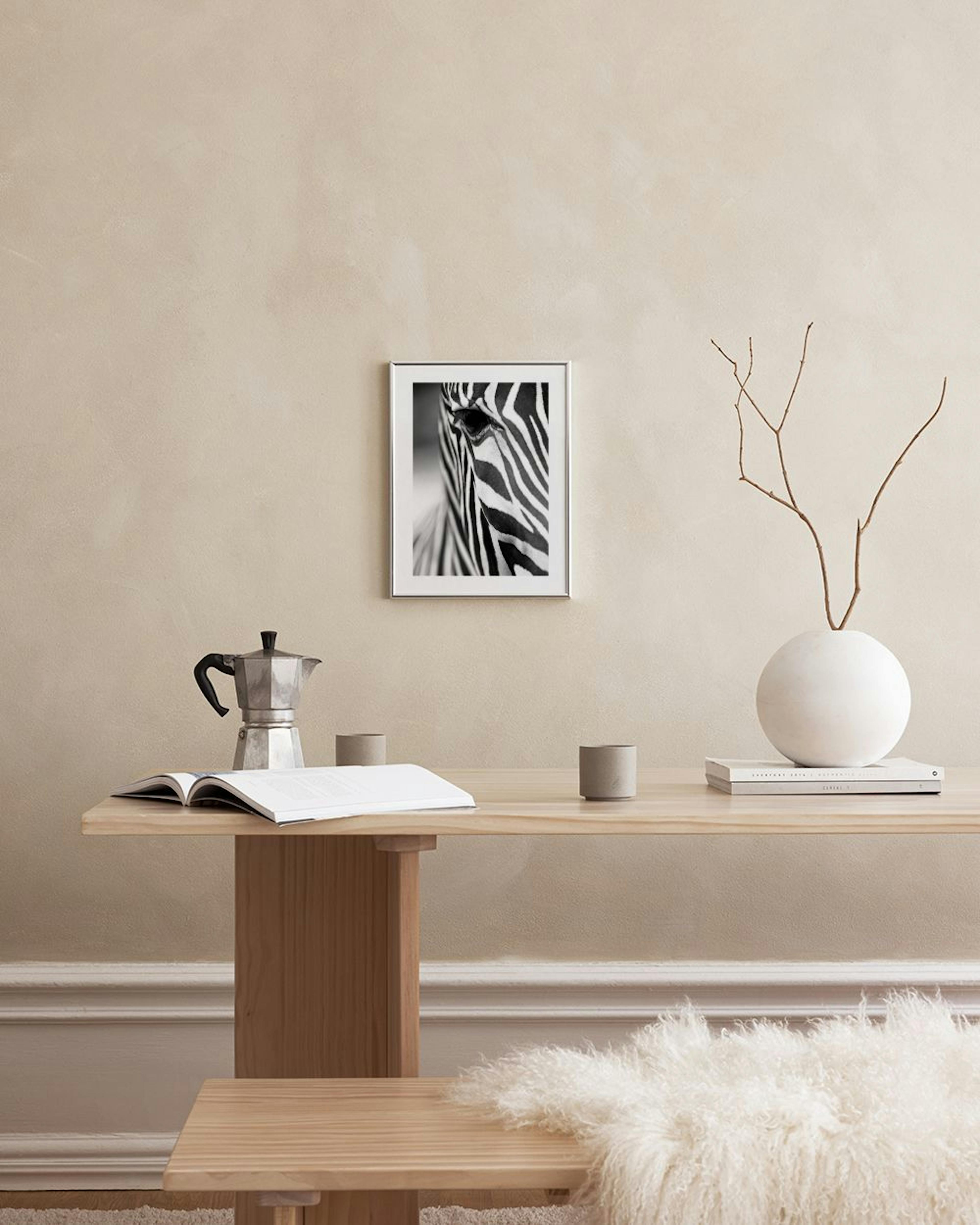 Schwarz-weiß Poster eines Zebraauges und Streifen, an einer grauen Wand über modernen Tischen mit goldenen Vasen.