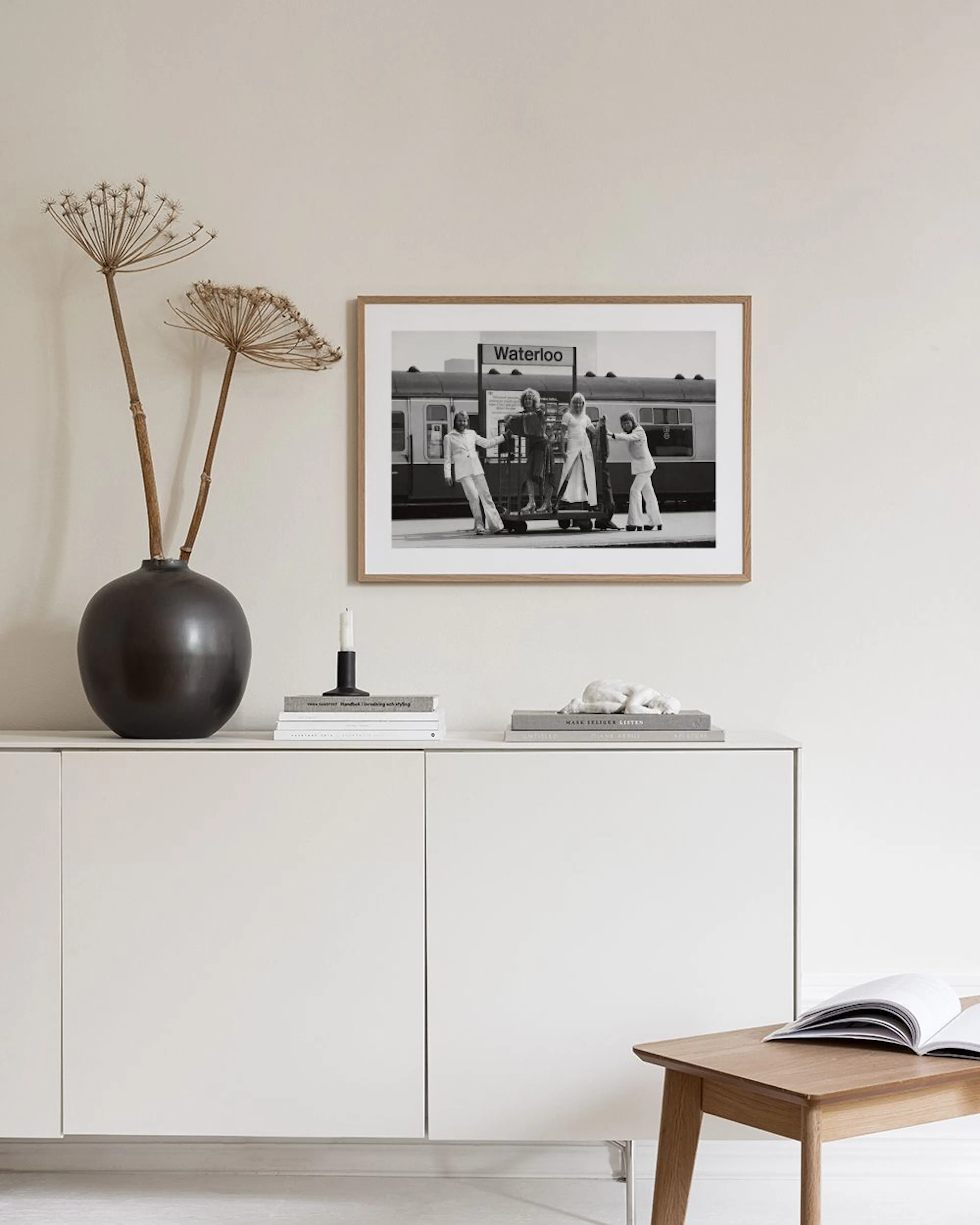 Schwarz-Weiß-Poster von ABBA am Bahnhof Waterloo, über einem Sideboard mit Vasen und Büchern.