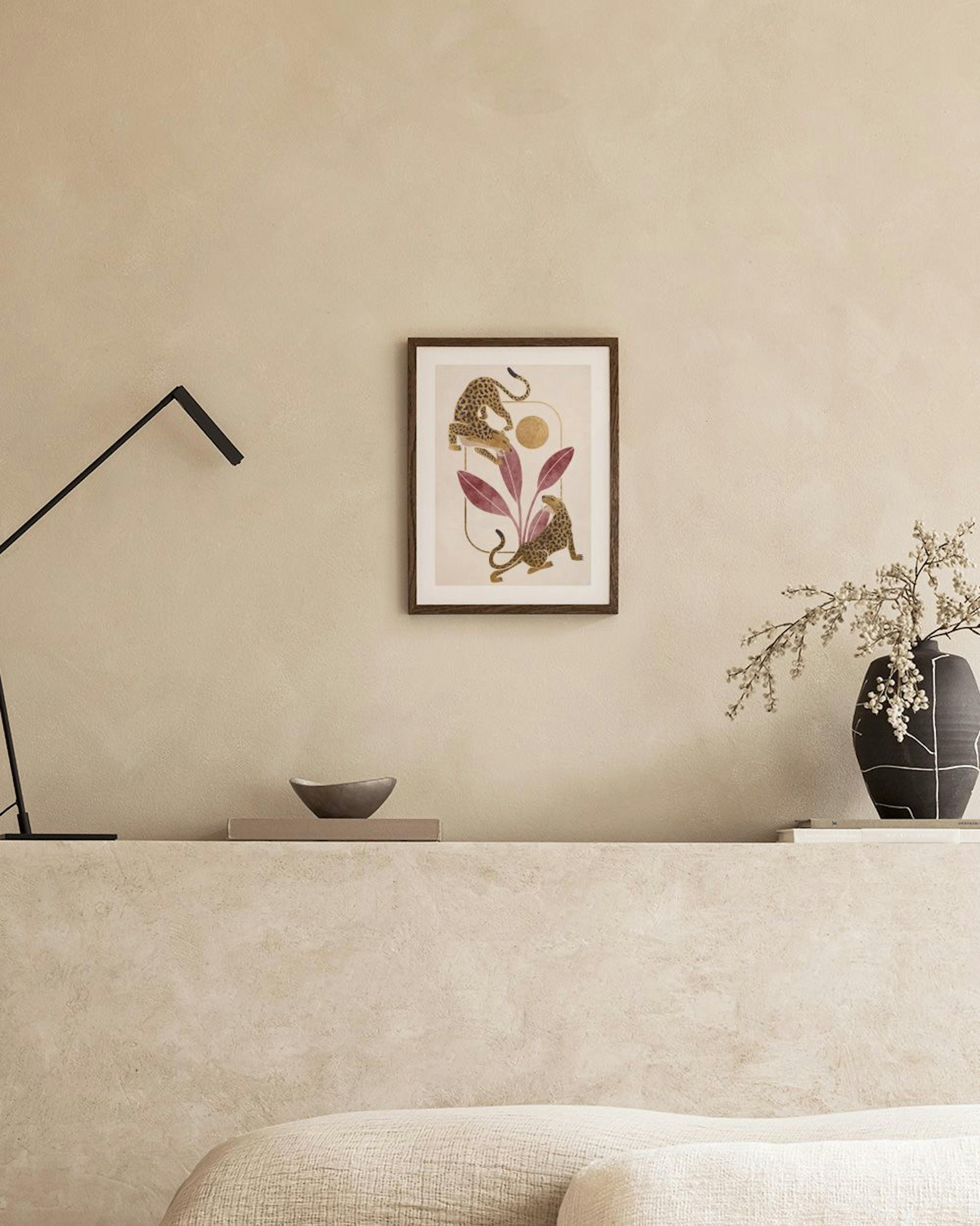 Póster de dos leopardos, plantas moradas y un sol dorado, colgado sobre un mueble blanco con un jarrón y libros.
