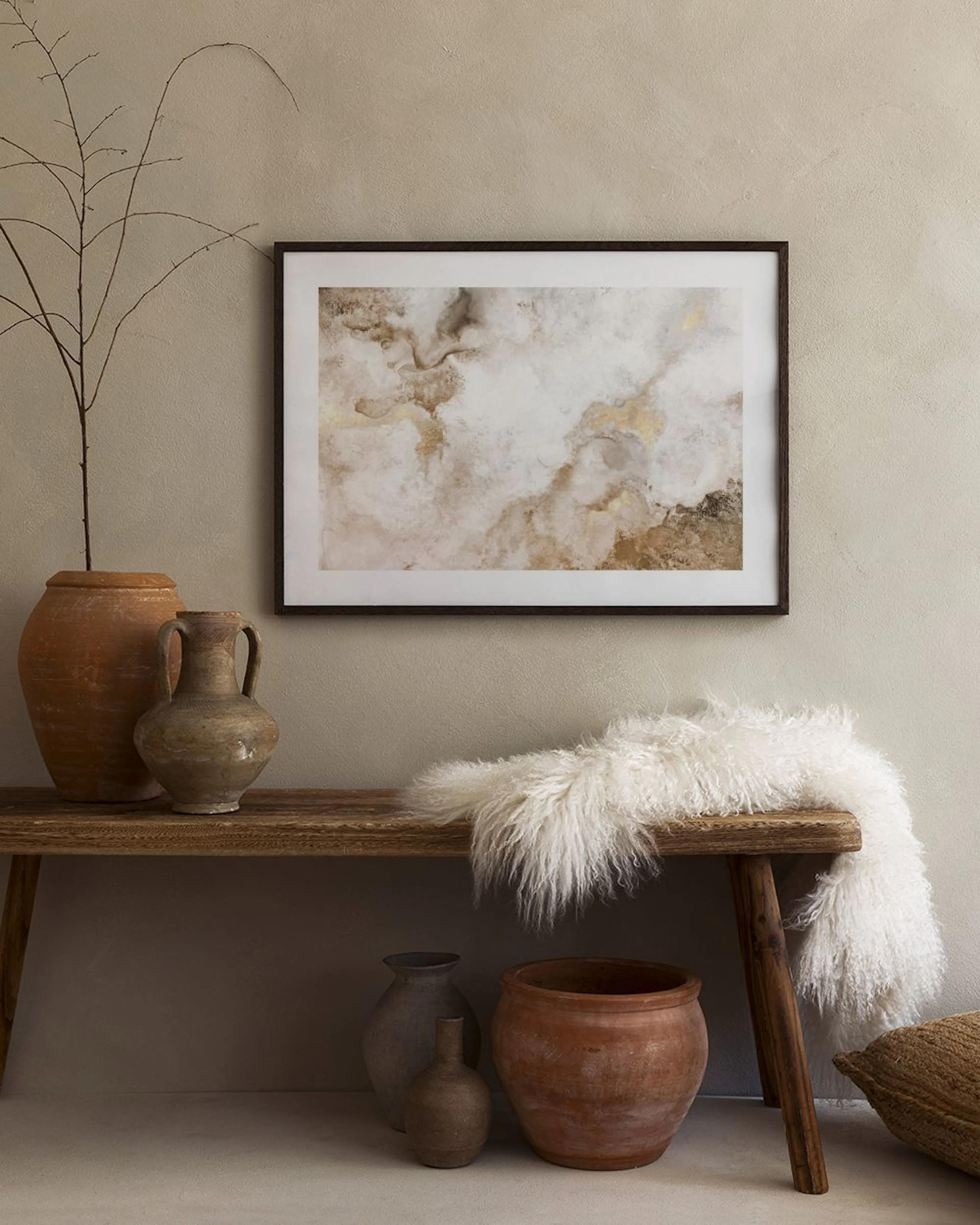 Affiche abstraite aux tons beige, or et blanc avec des formes organiques, suspendue au-dessus dune console noire dans une chambr