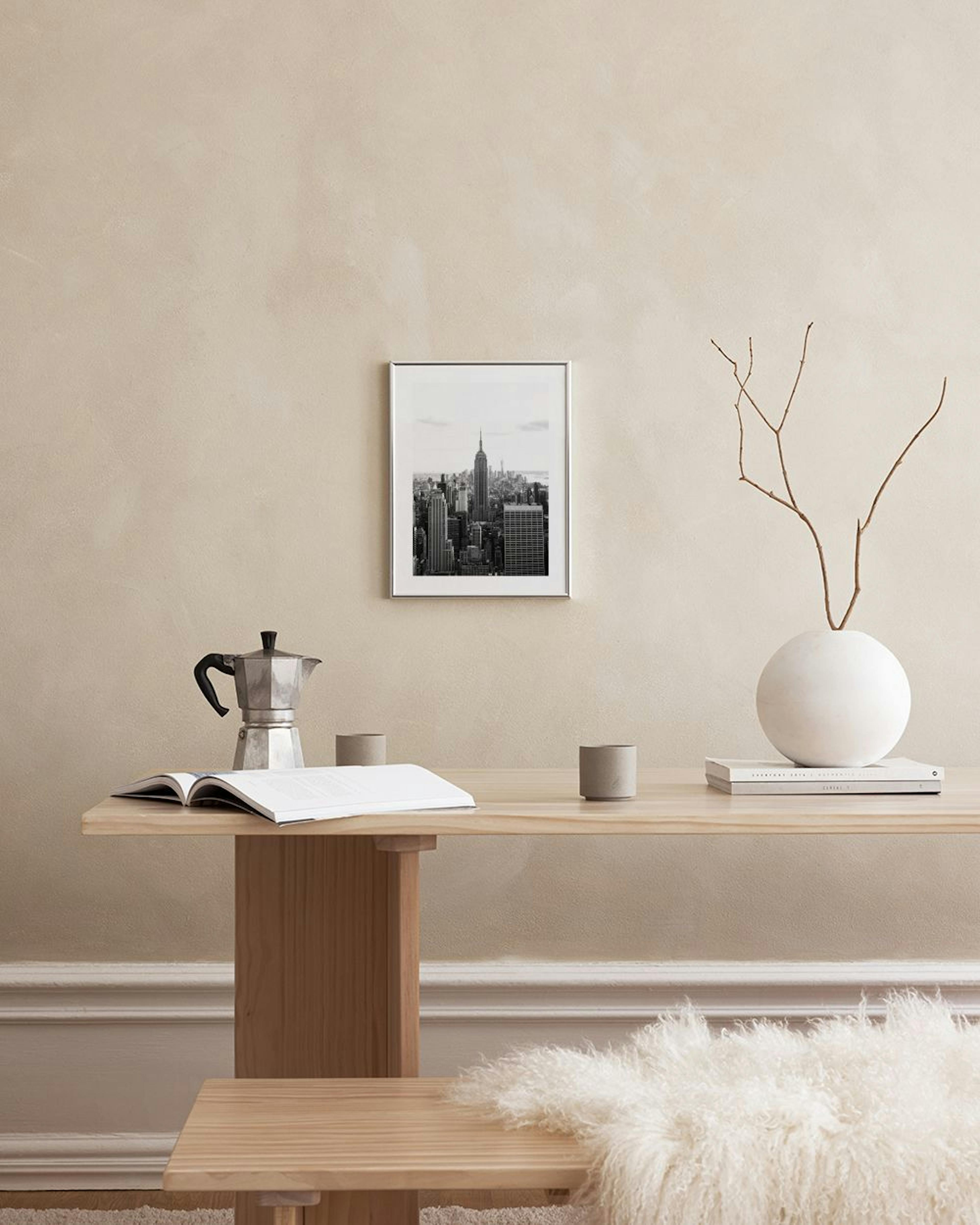 A black and white city print featuring the Empire State Building, displayed in a modern living room above a white cabinet.