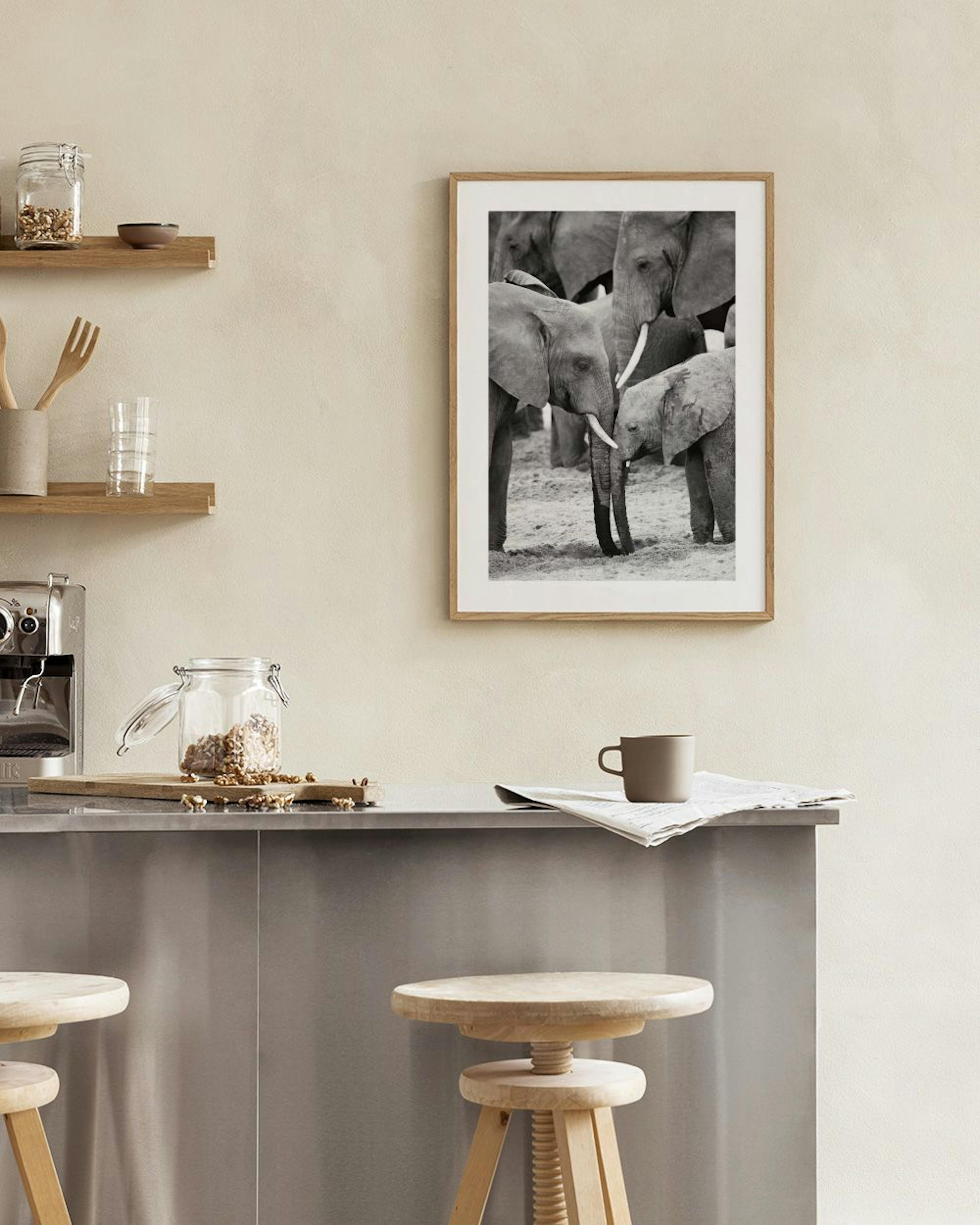 A black and white print of elephants, with a baby elephant nuzzling its mother, hanging above a light gray armchair in a modern 