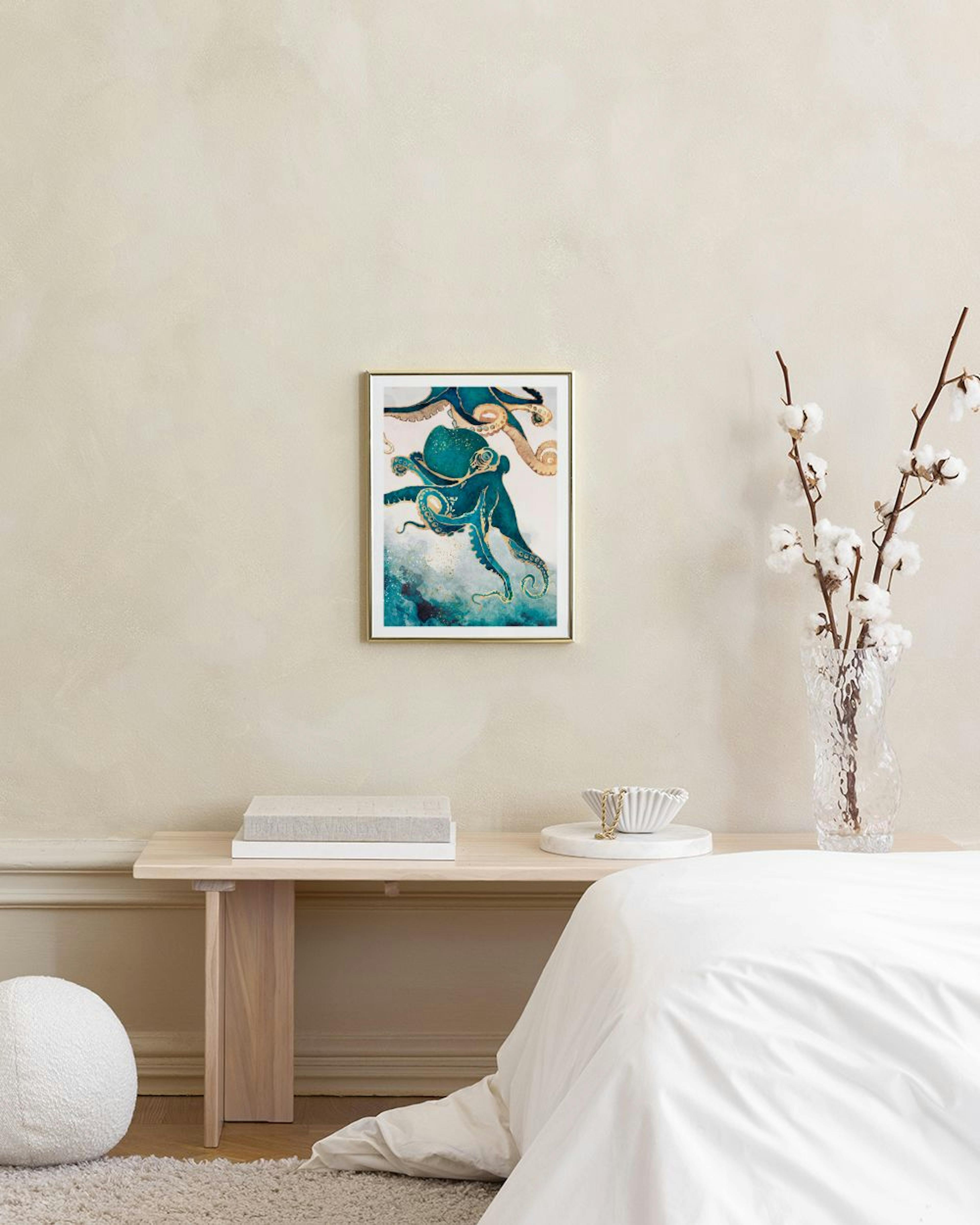 Plakat med blæksprutte i blå og guld, hængende over et fletmøbel med bøger og vase i et lyst rum.