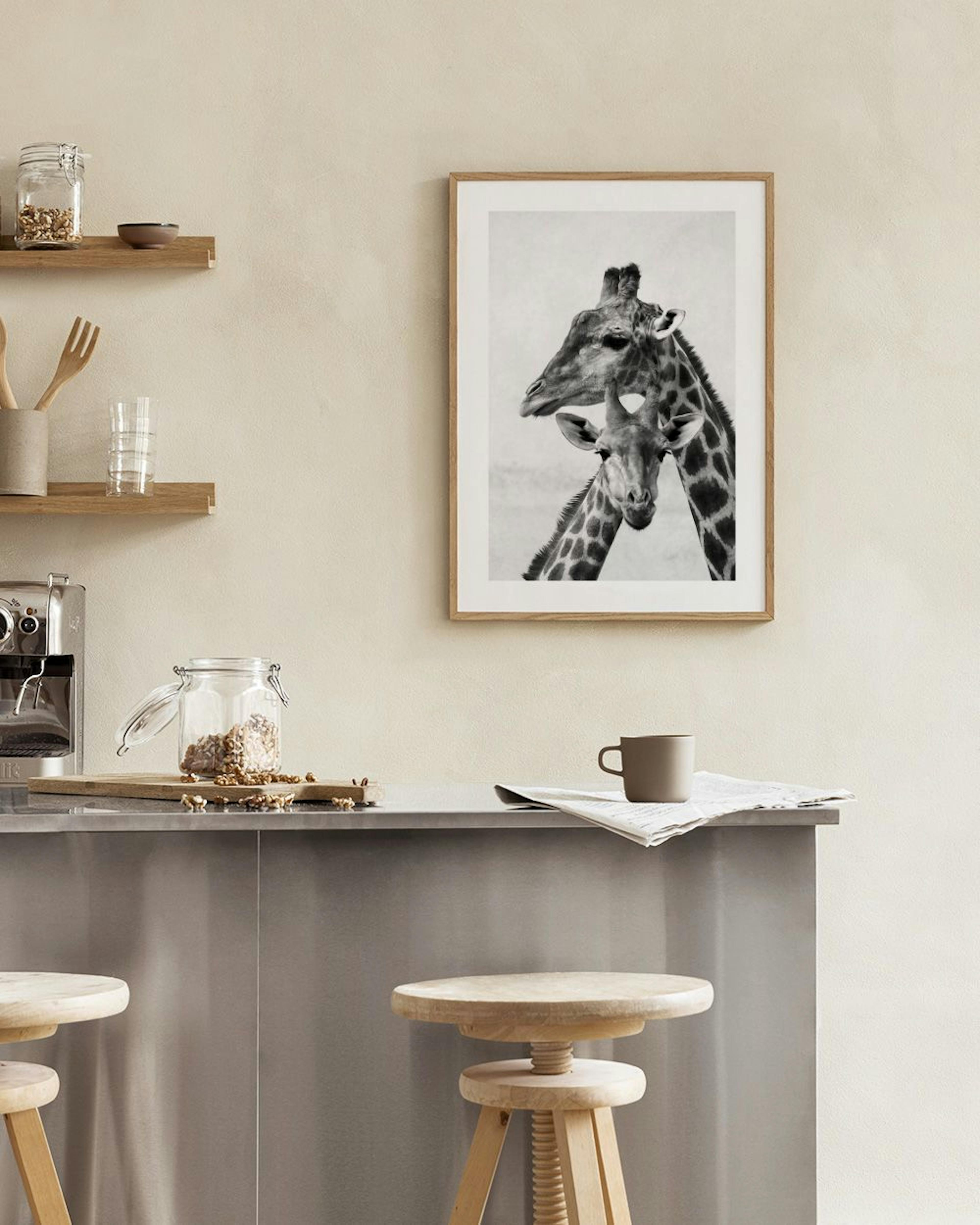 A black and white print of a mother and baby giraffe, displayed above a white cabinet with books and a vase.
