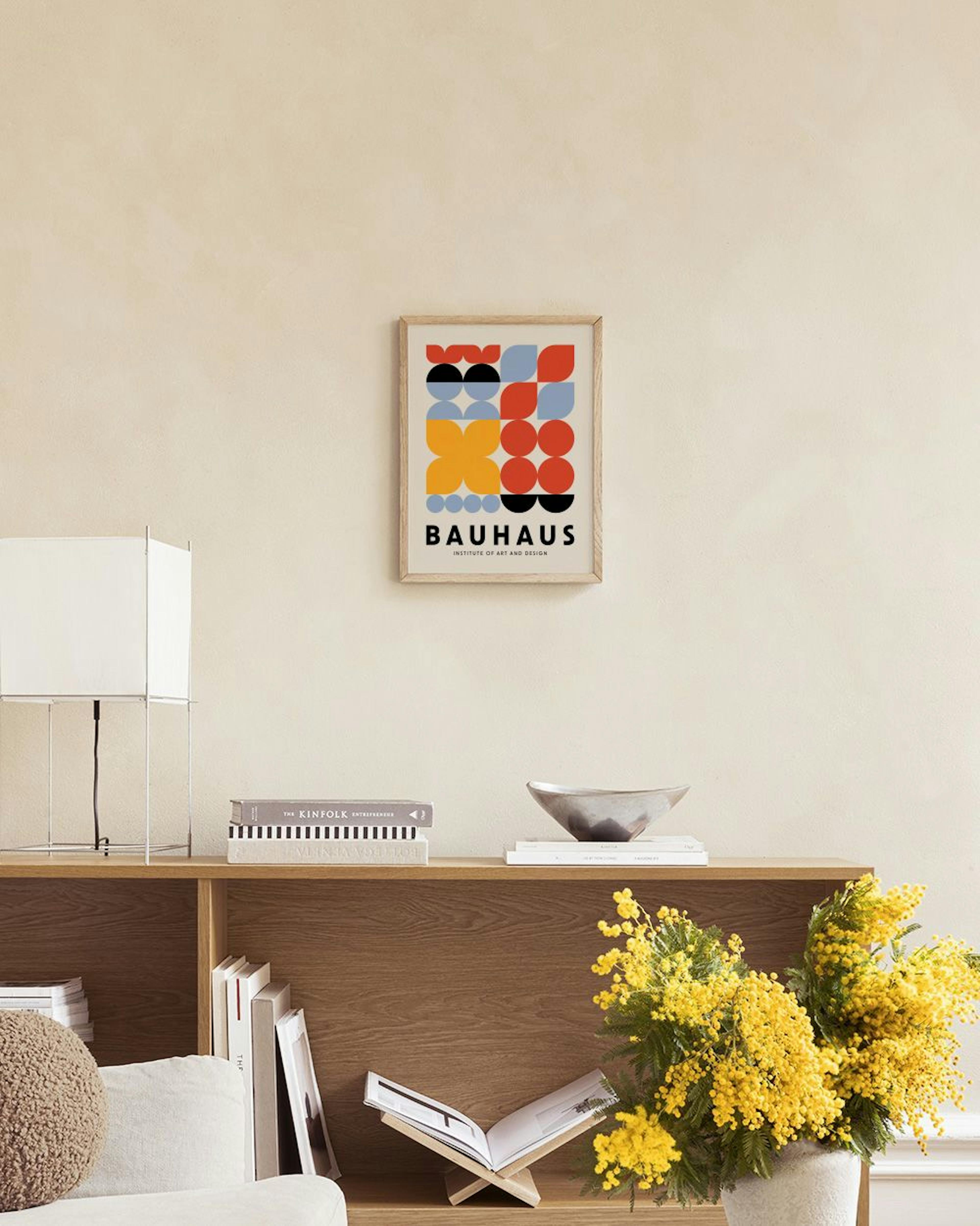 Poster Bauhaus con motivi geometrici rossi, blu, gialli e neri, appeso sopra una panca di legno con vasi.