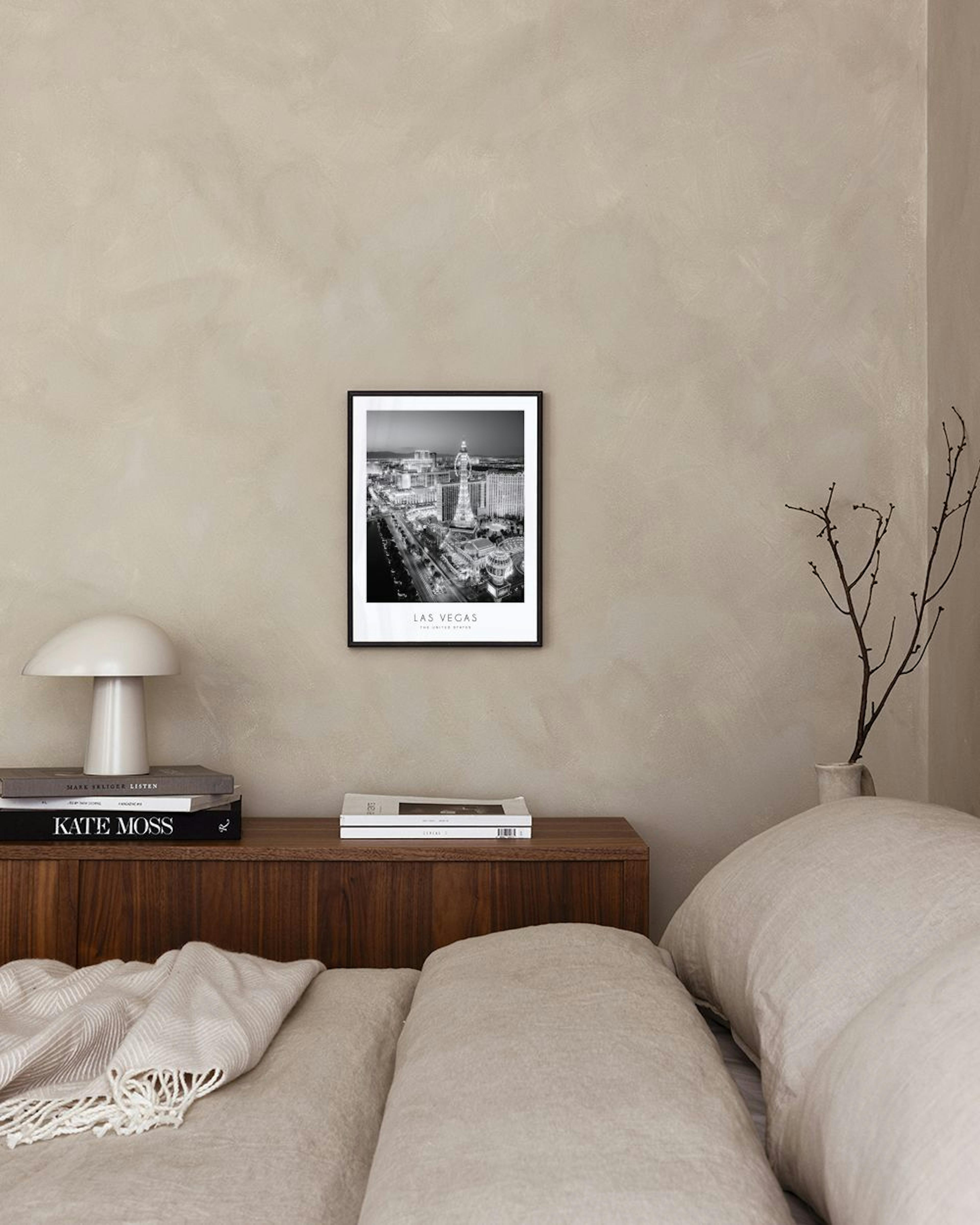 Black and white print of the Las Vegas Strip at night, hanging above a black console table with books and a plant.