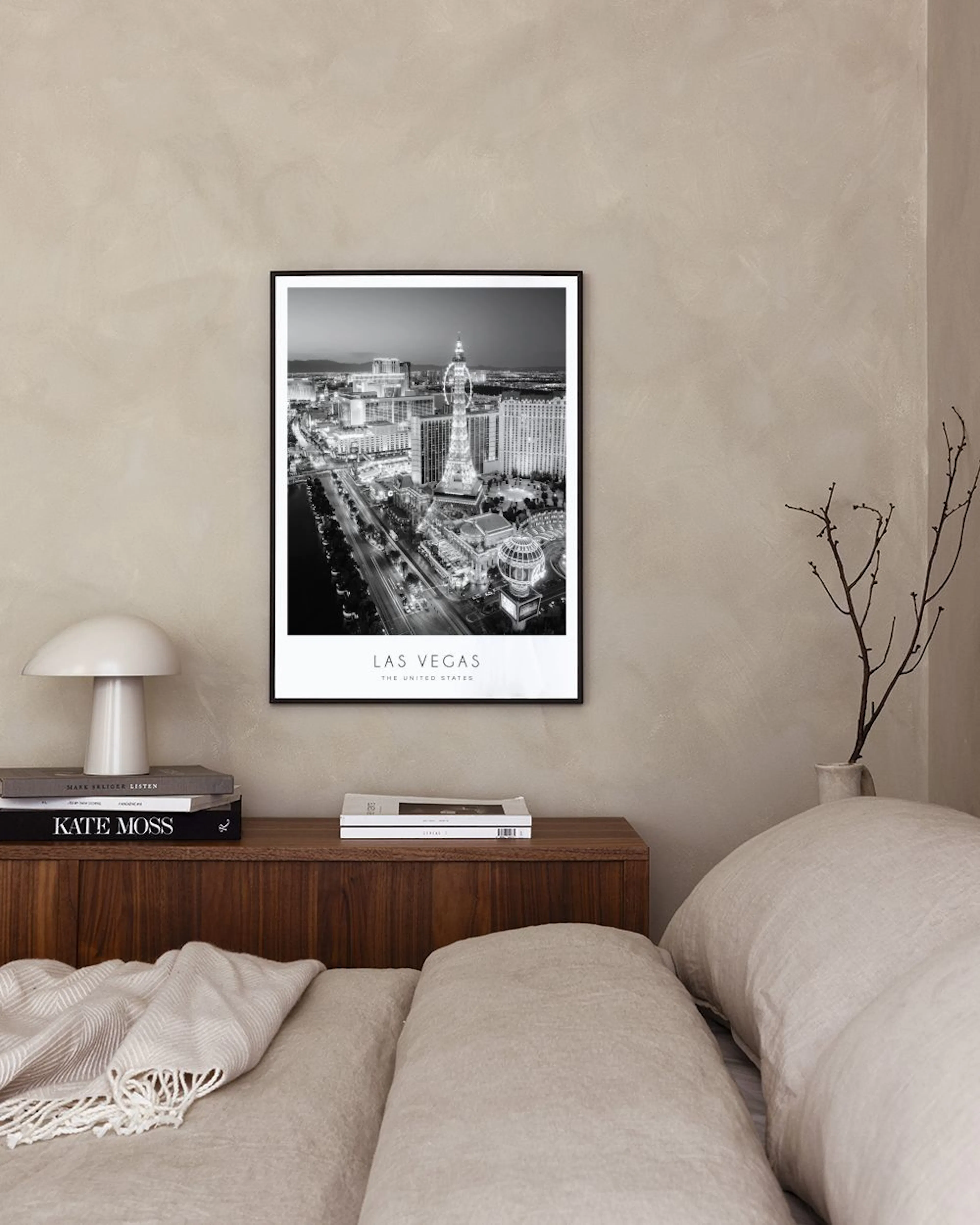 Zwart-wit poster van de skyline van Las Vegas met lichten, hangend boven een zwarte tafel met boeken en een plant.