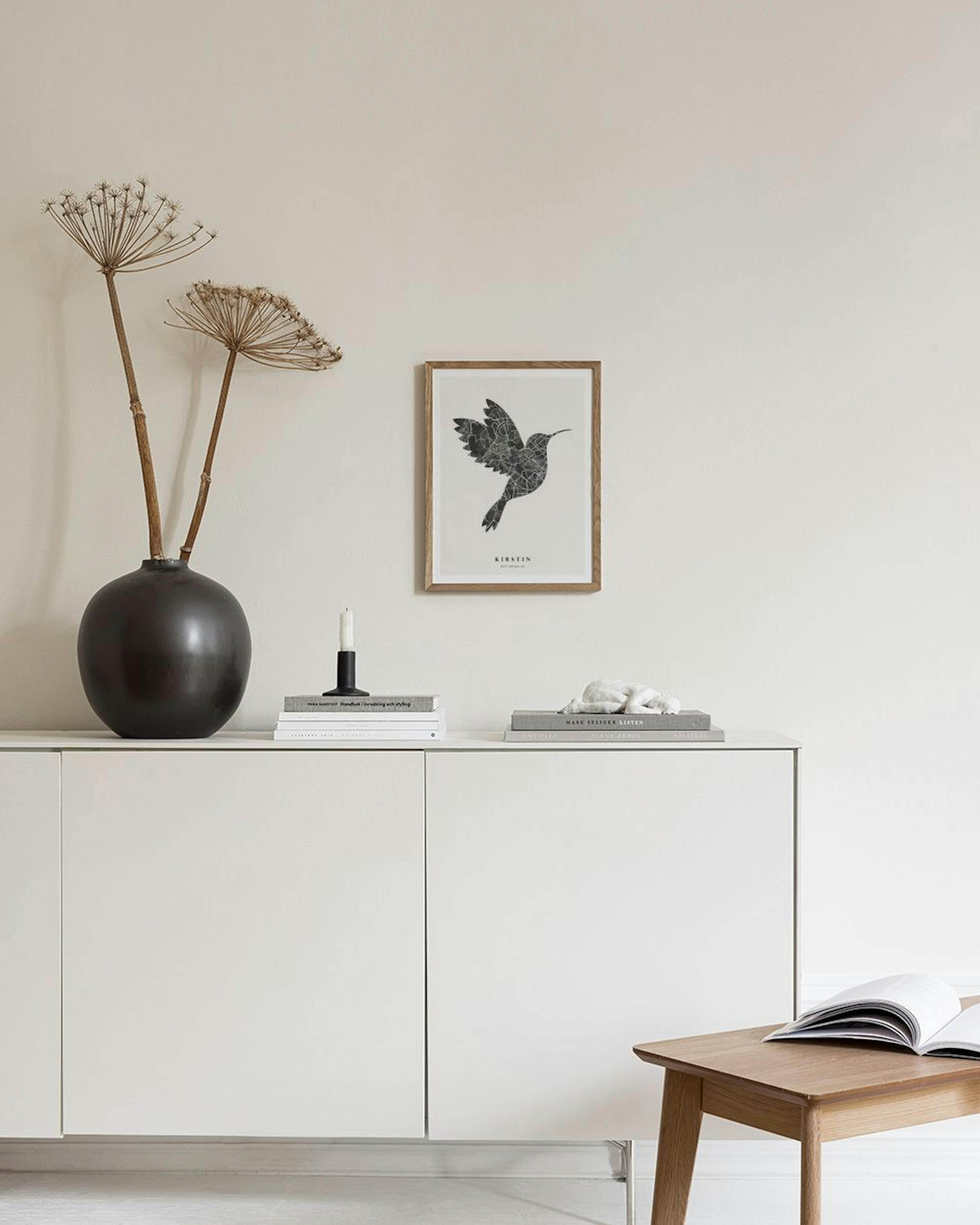 Poster personalizzato con sagoma di colibrì formata da mappa stradale, appeso sopra una poltrona verde con un vaso.