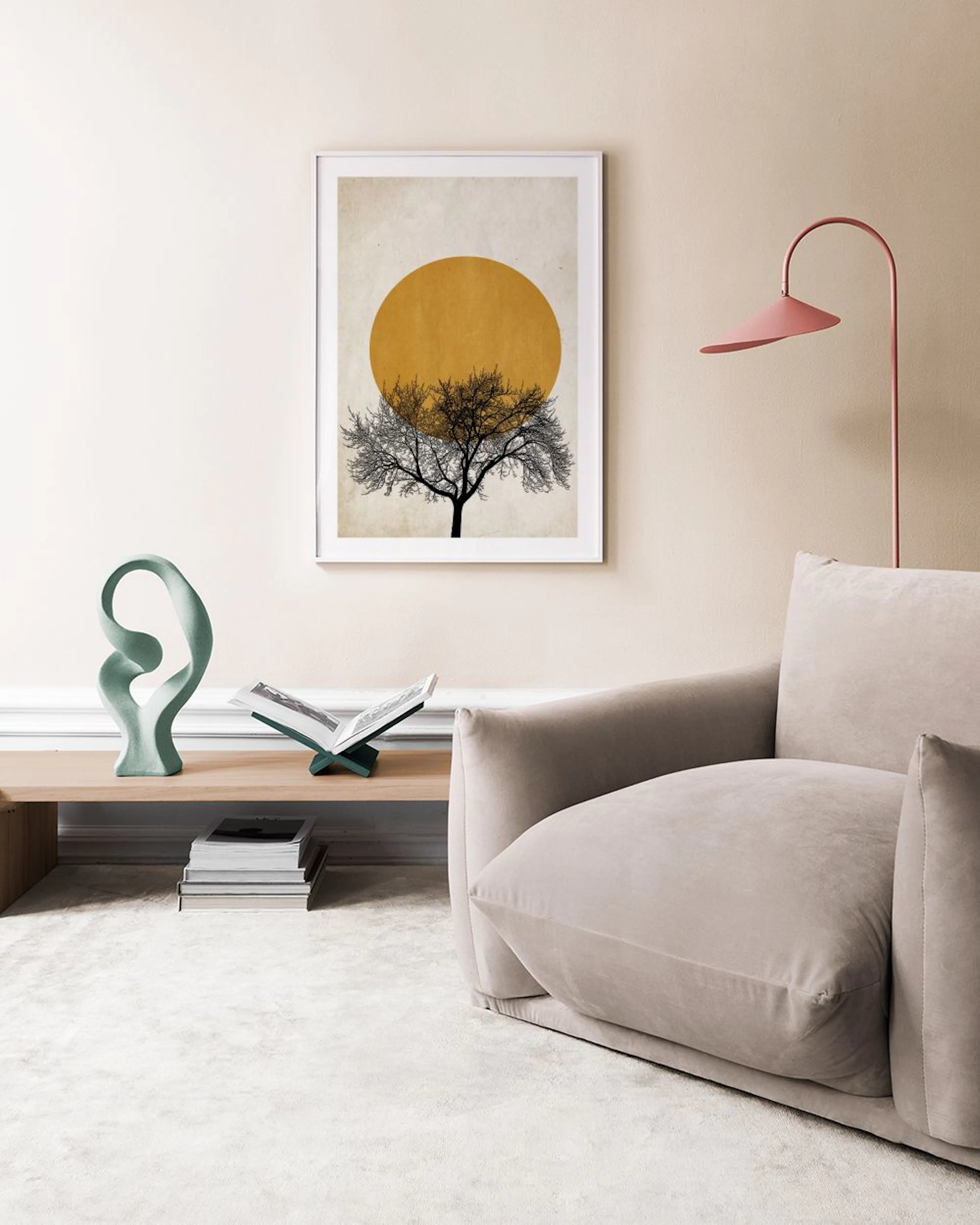 A print of a dark bare tree against a mustard yellow circle, displayed on a white cabinet with a vase and decorative objects.