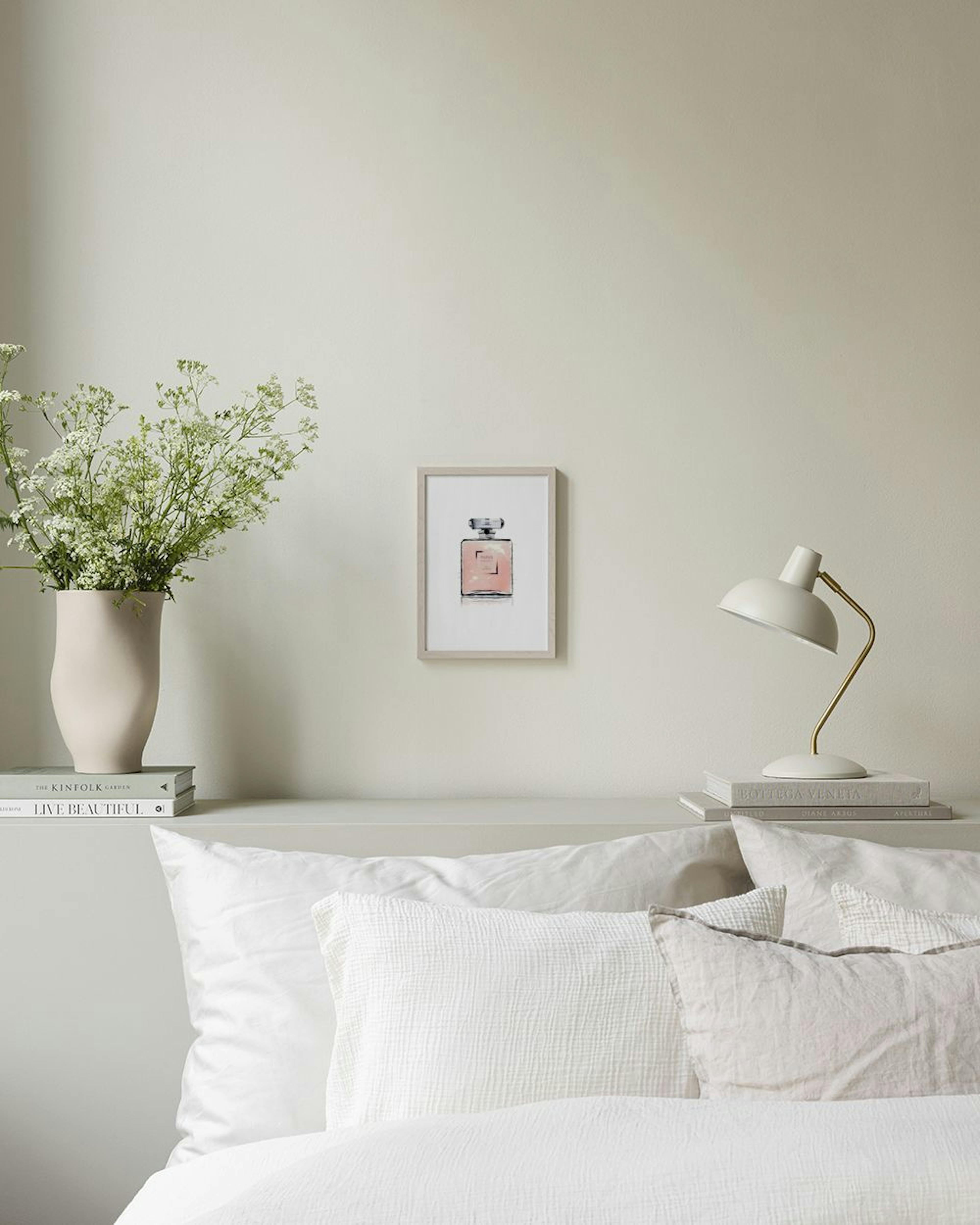 Póster de una botella de perfume rosa con la palabra PARIS colgando en una sala con un sillón rosa y un sofá blanco.