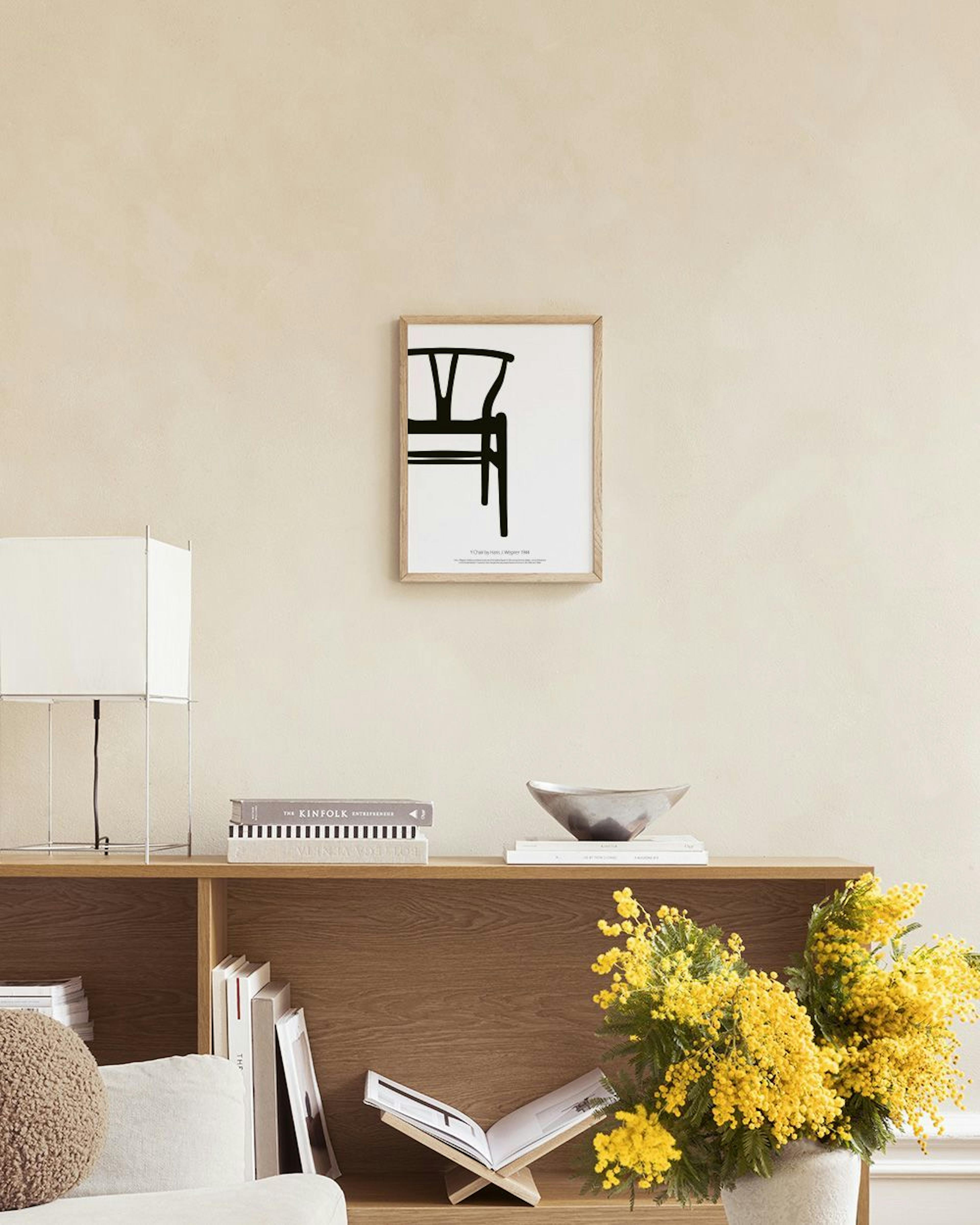 Dois posters minimalistas a preto e branco de um e-comercial e uma cadeira, sobre um aparador branco com vasos e livros.