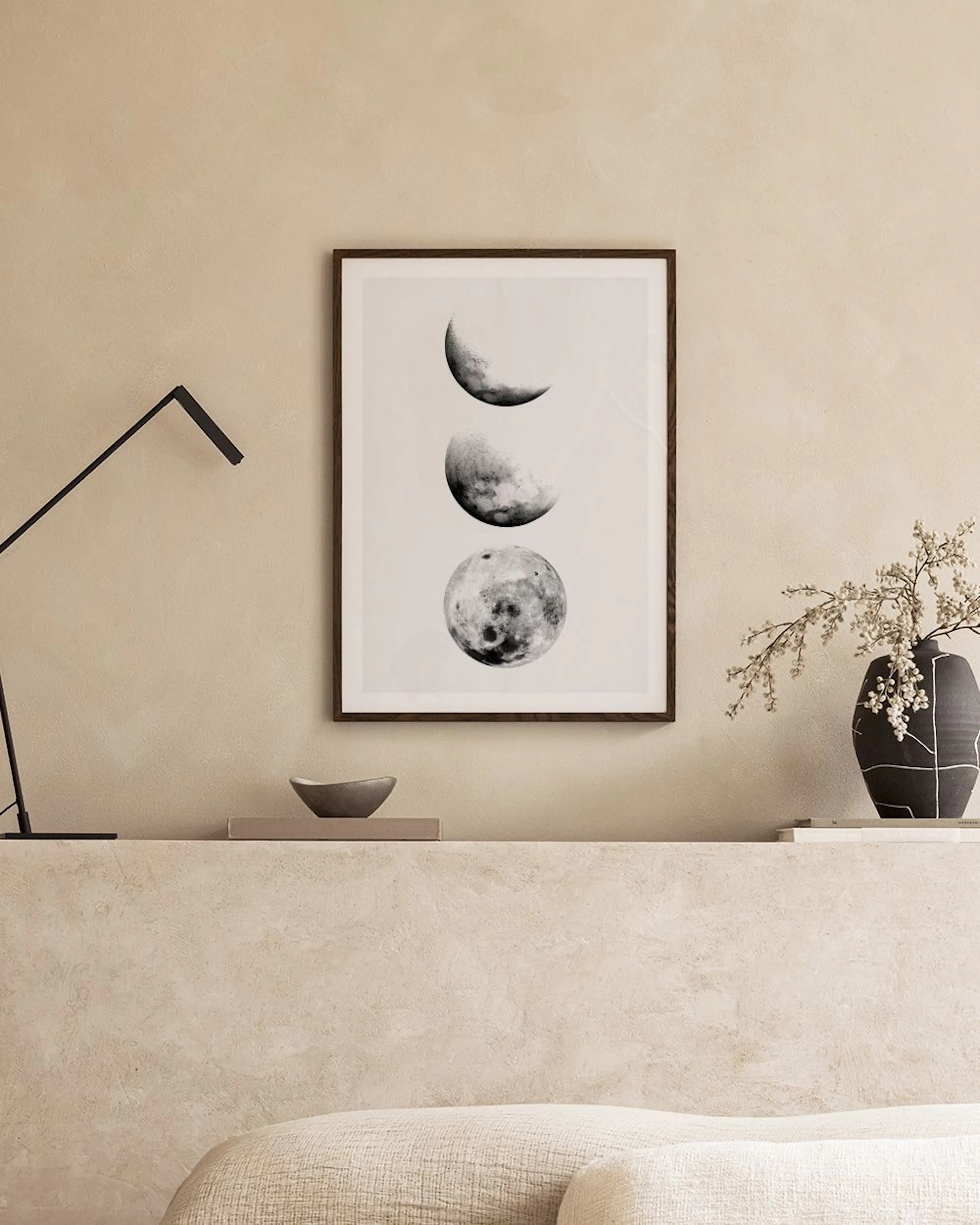 Affiche noire et blanche des phases de la lune, posée sur une étagère avec un cactus et un chandelier.