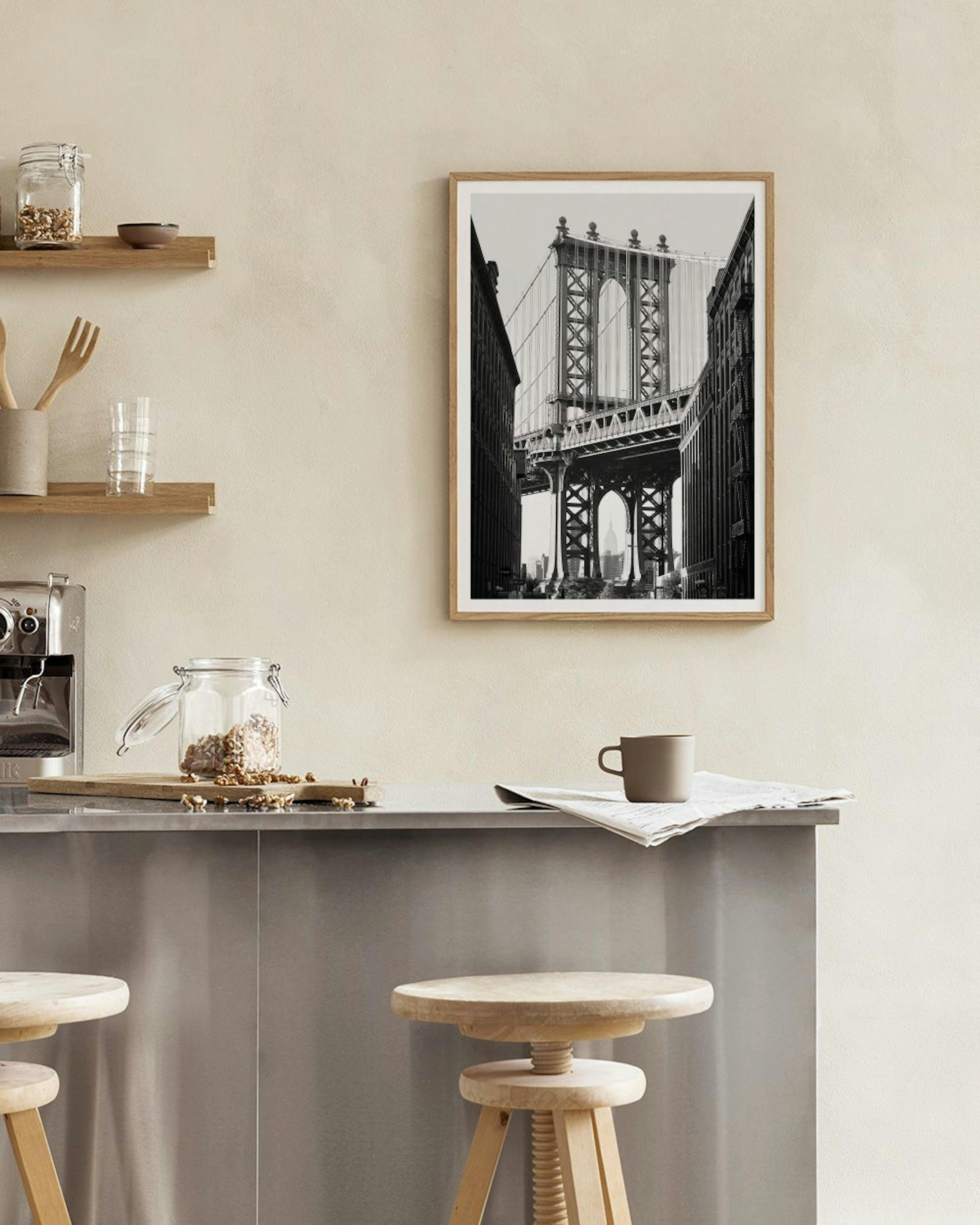 Black and white print of the Manhattan Bridge, displayed on a white shelf with a potted cactus and gold candle holder.