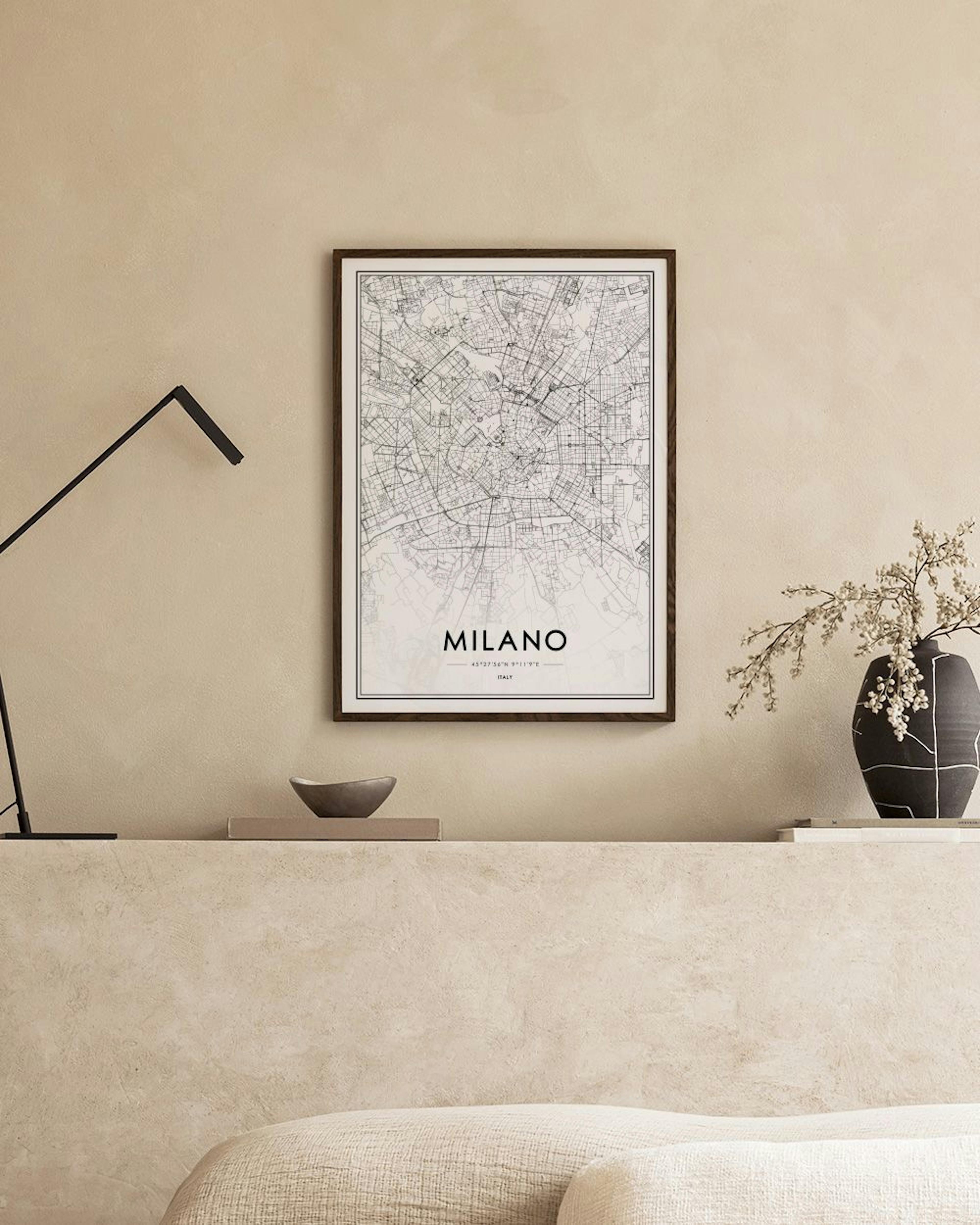 Poster con mappa di Milano in bianco e nero, appeso sopra una consolle nera con libri e piante.