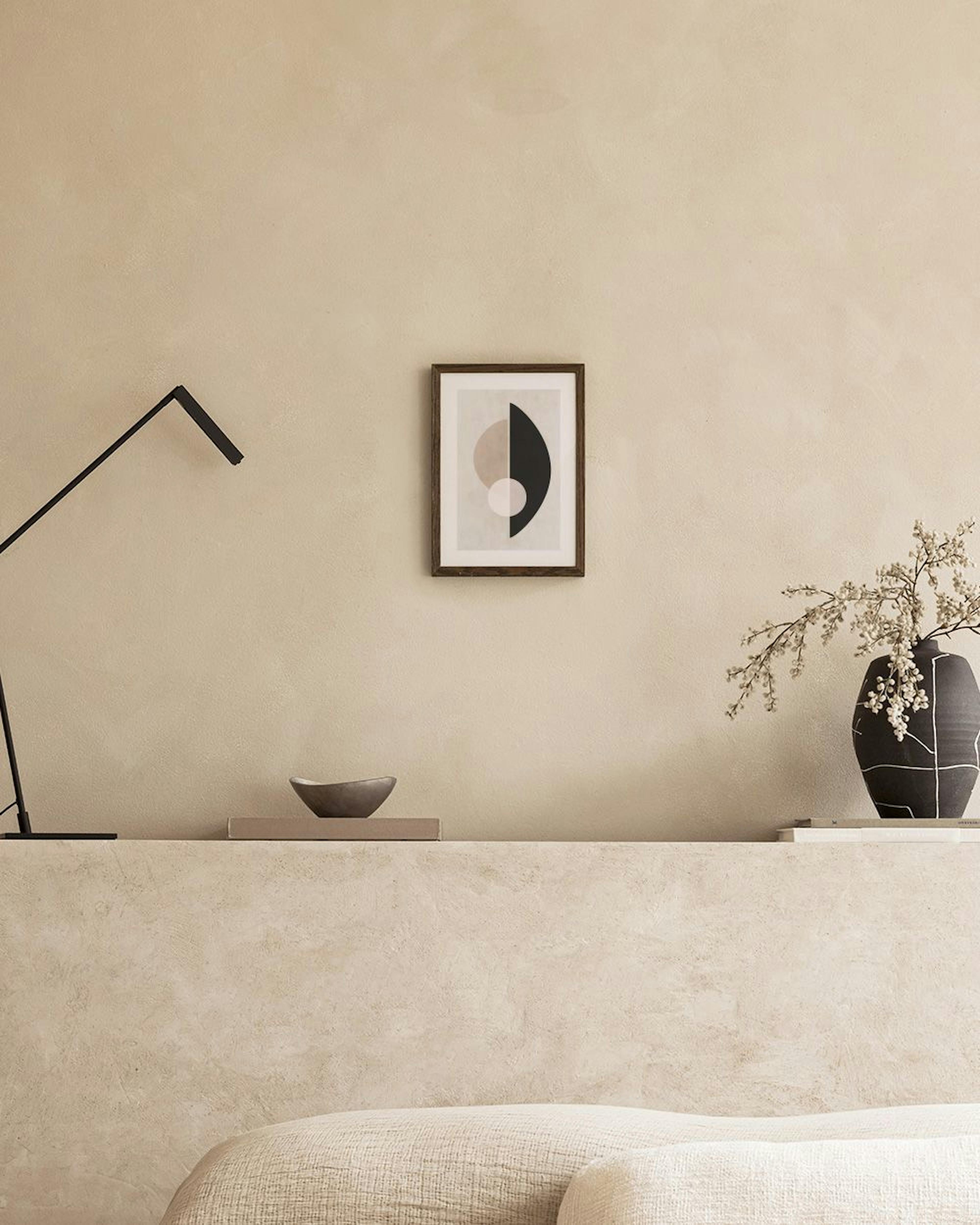 Poster met abstracte vormen in beige, zwart en wit, hangend in een modern interieur boven een poef.