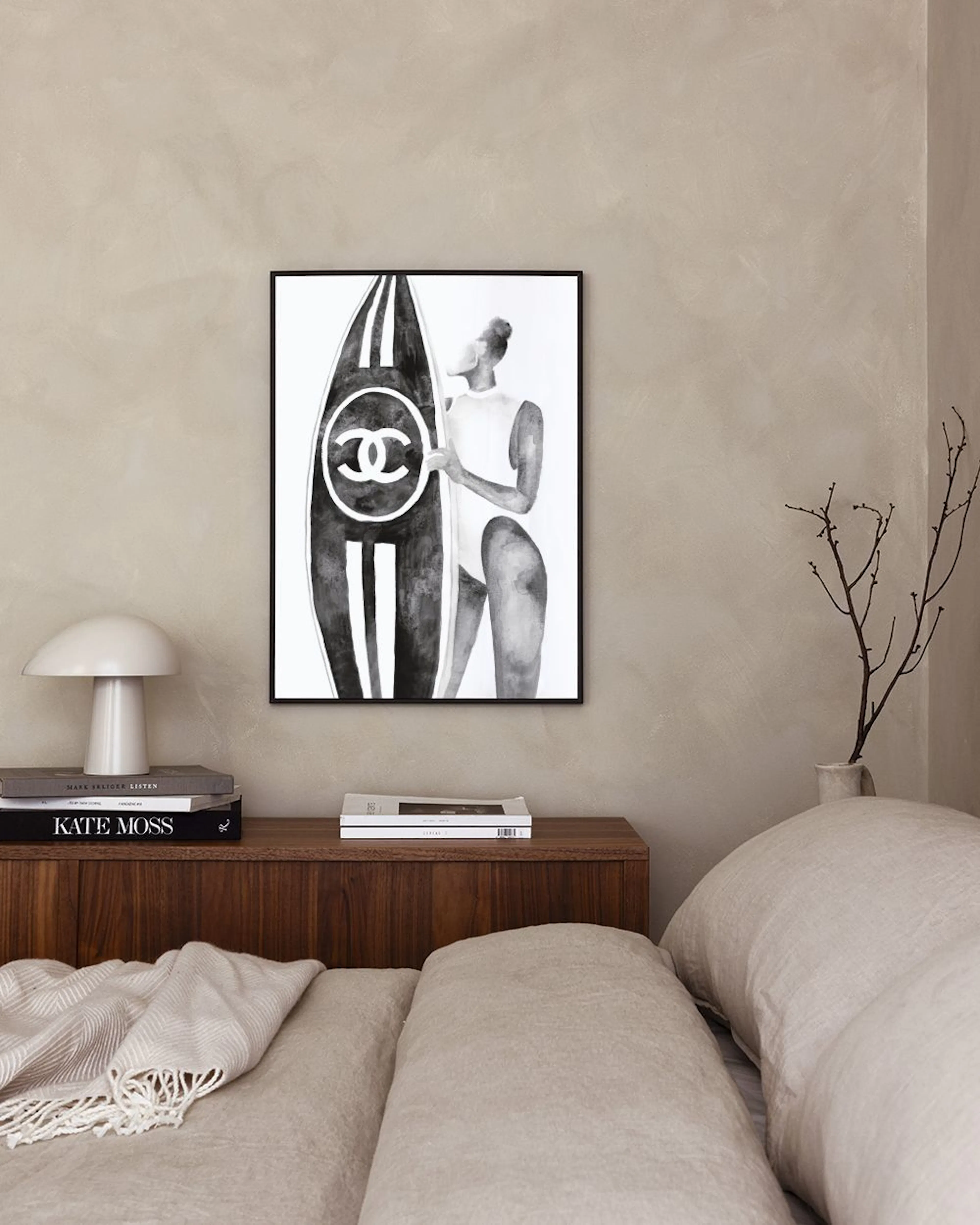Affiche noir et blanc dune femme en maillot avec une planche de surf Chanel, affichée au-dessus dun buffet.