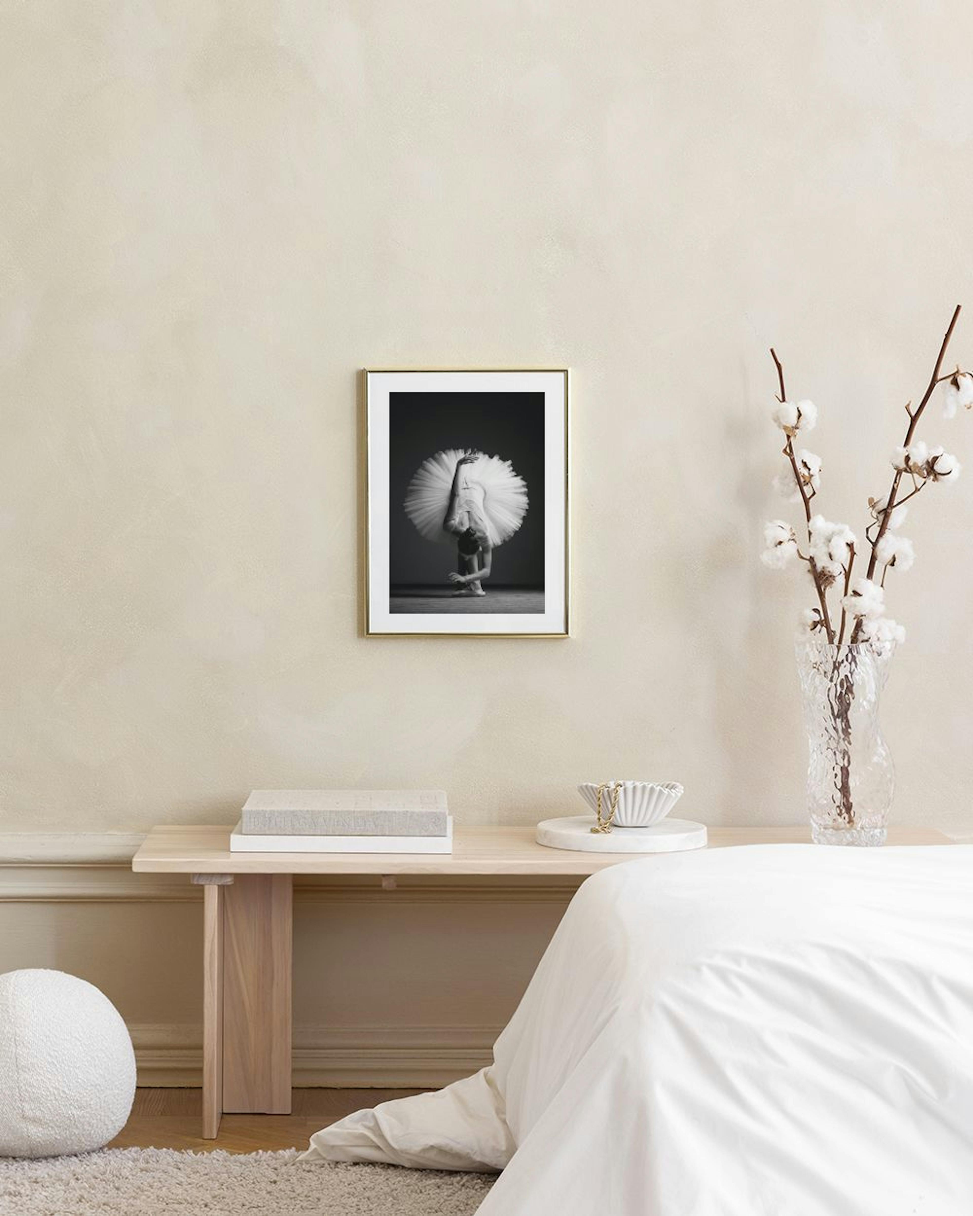 Zwart-wit poster van een ballerina in een tutu, voorovergebogen op de grond, hangend in een modern interieur.