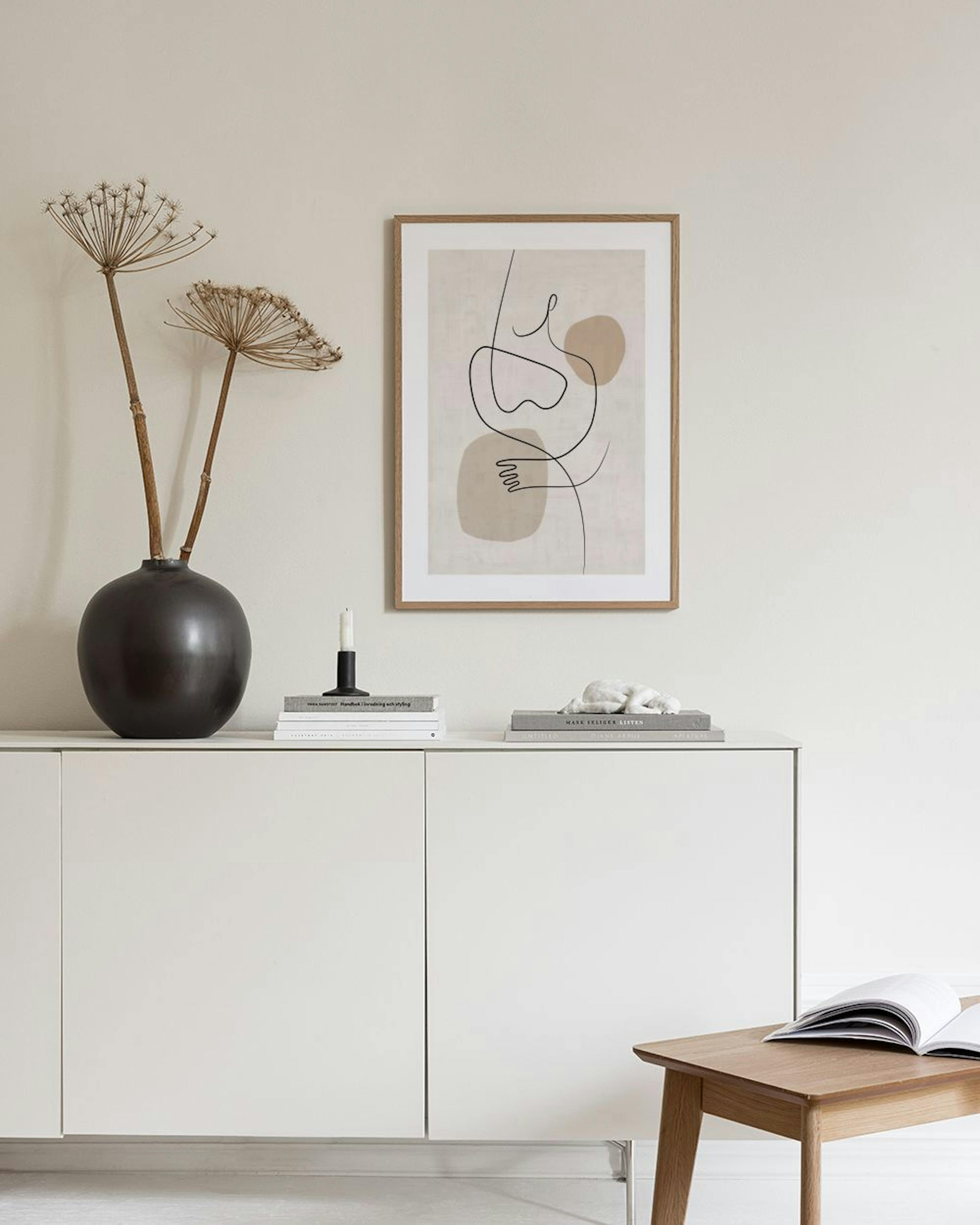 Abstract line art print with black lines forming shapes and beige organic shapes, displayed above a white cabinet.