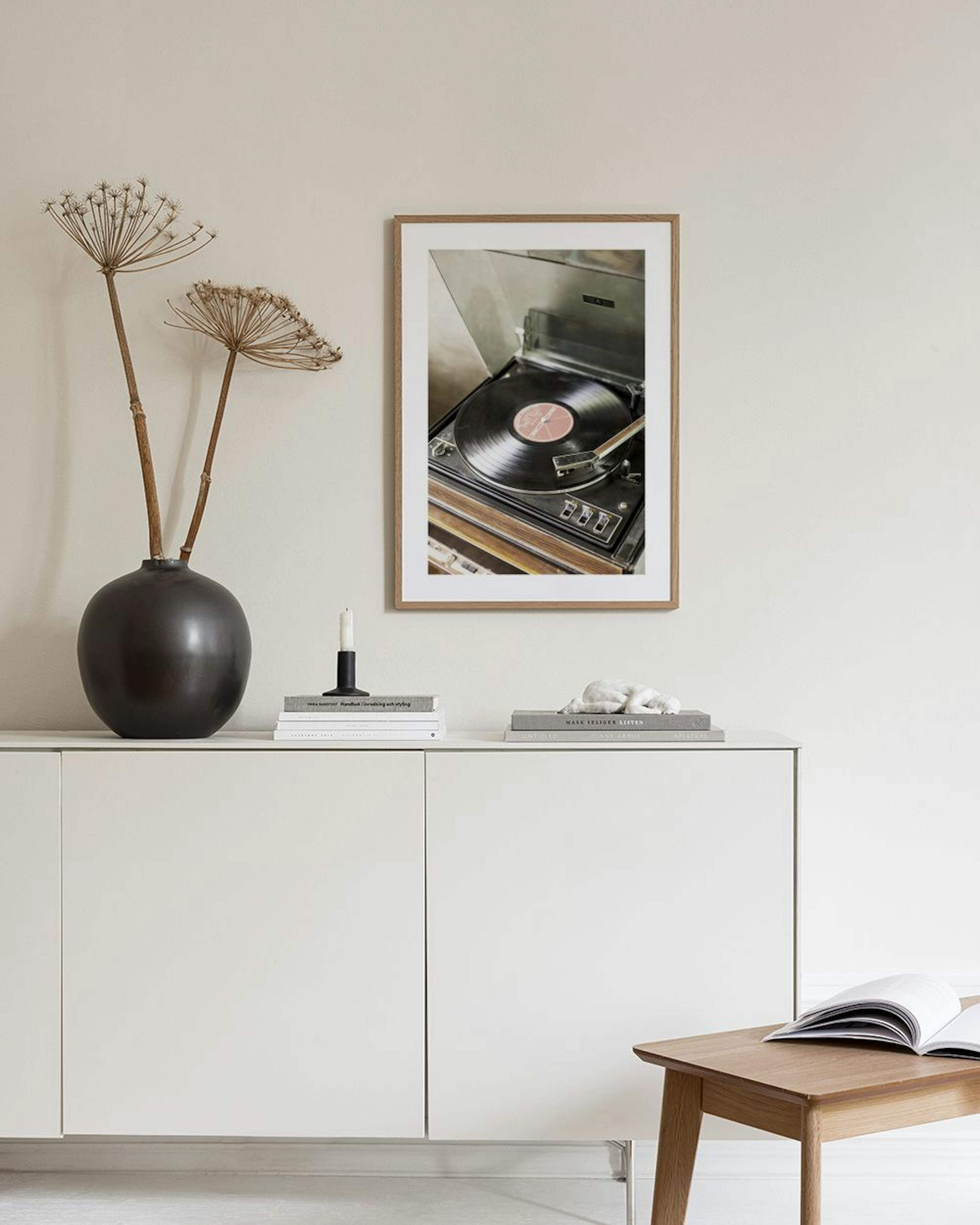 A print of a vintage record player with a vinyl record, displayed above a white bouclé armchair in a living room.