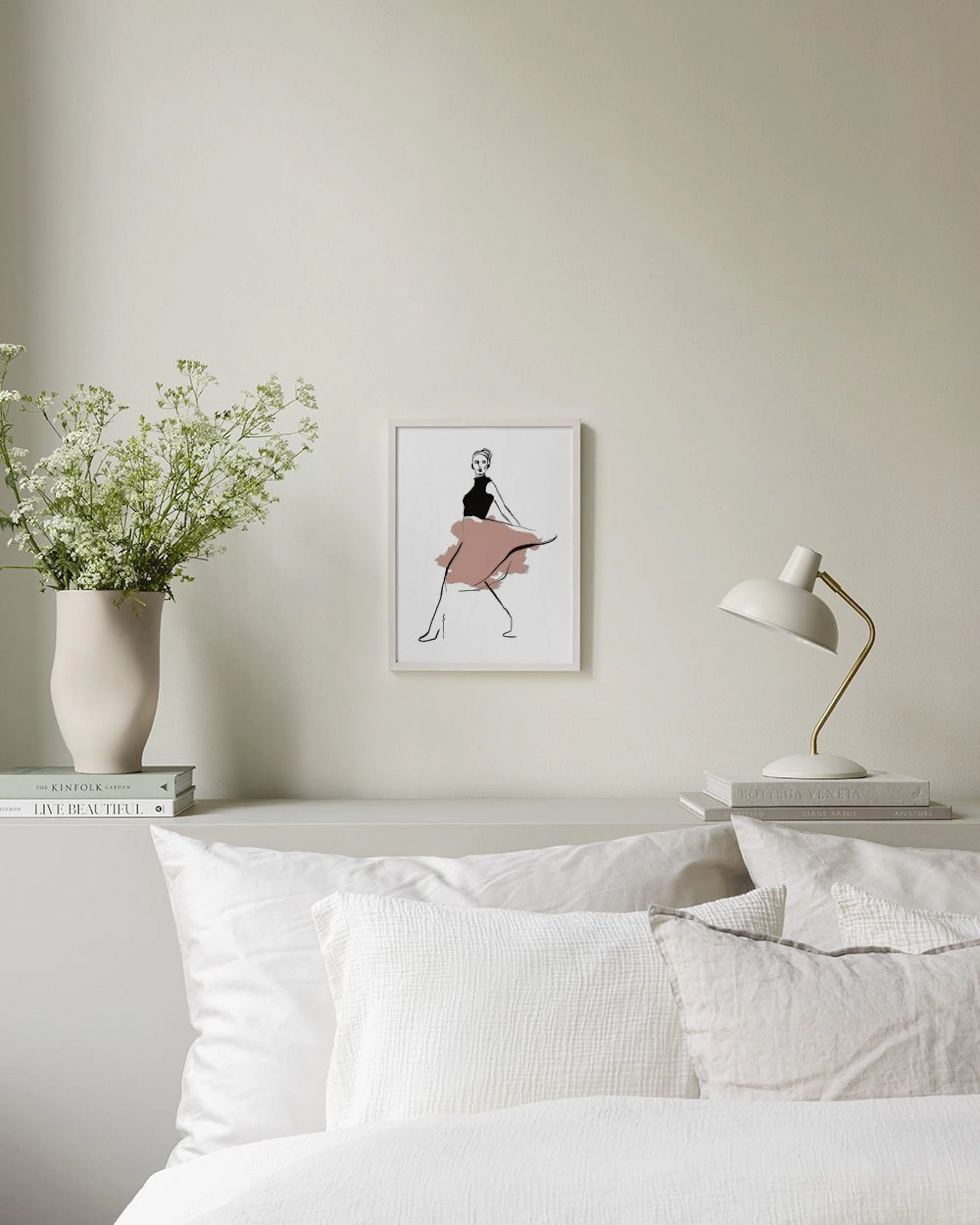 Póster de ilustración femenina con falda rosa y top negro, sobre una mesa gris con objetos de decoración.