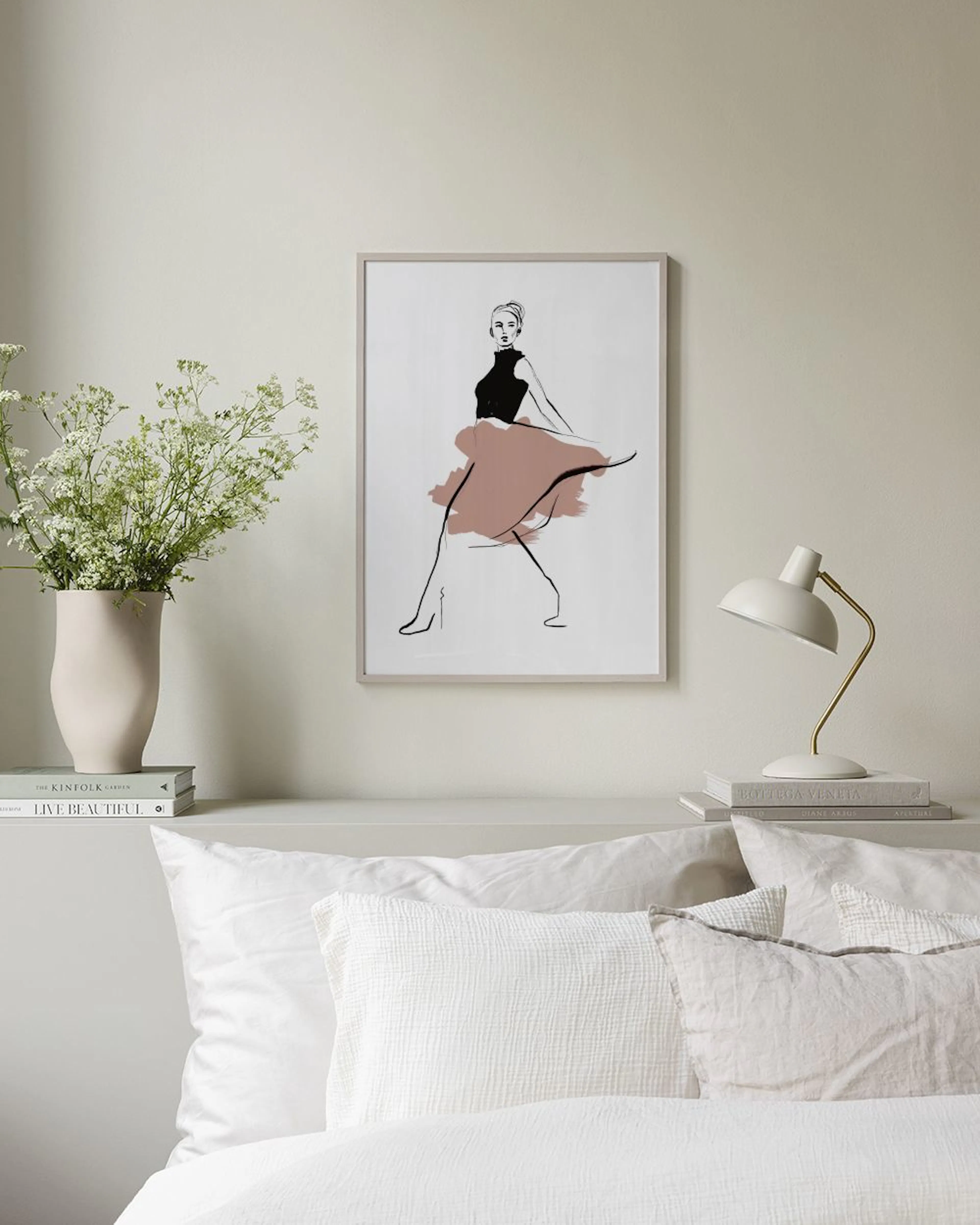 Fashion illustration print of a woman in a black top and pink flowing skirt, displayed on a grey bench.