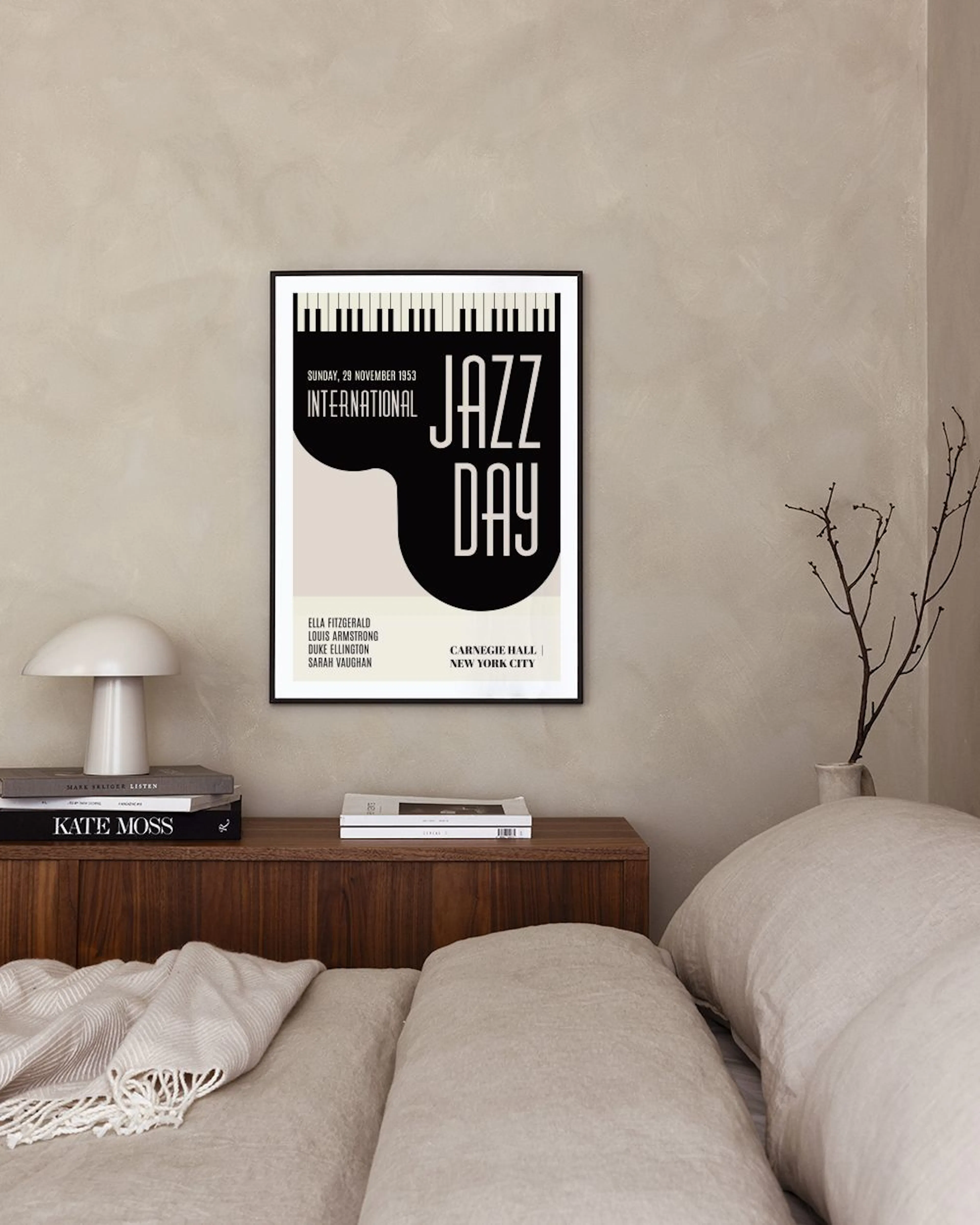 A black and beige Jazz Day print with piano keys, hanging above a white console table with a vase and books, next to a cane chai