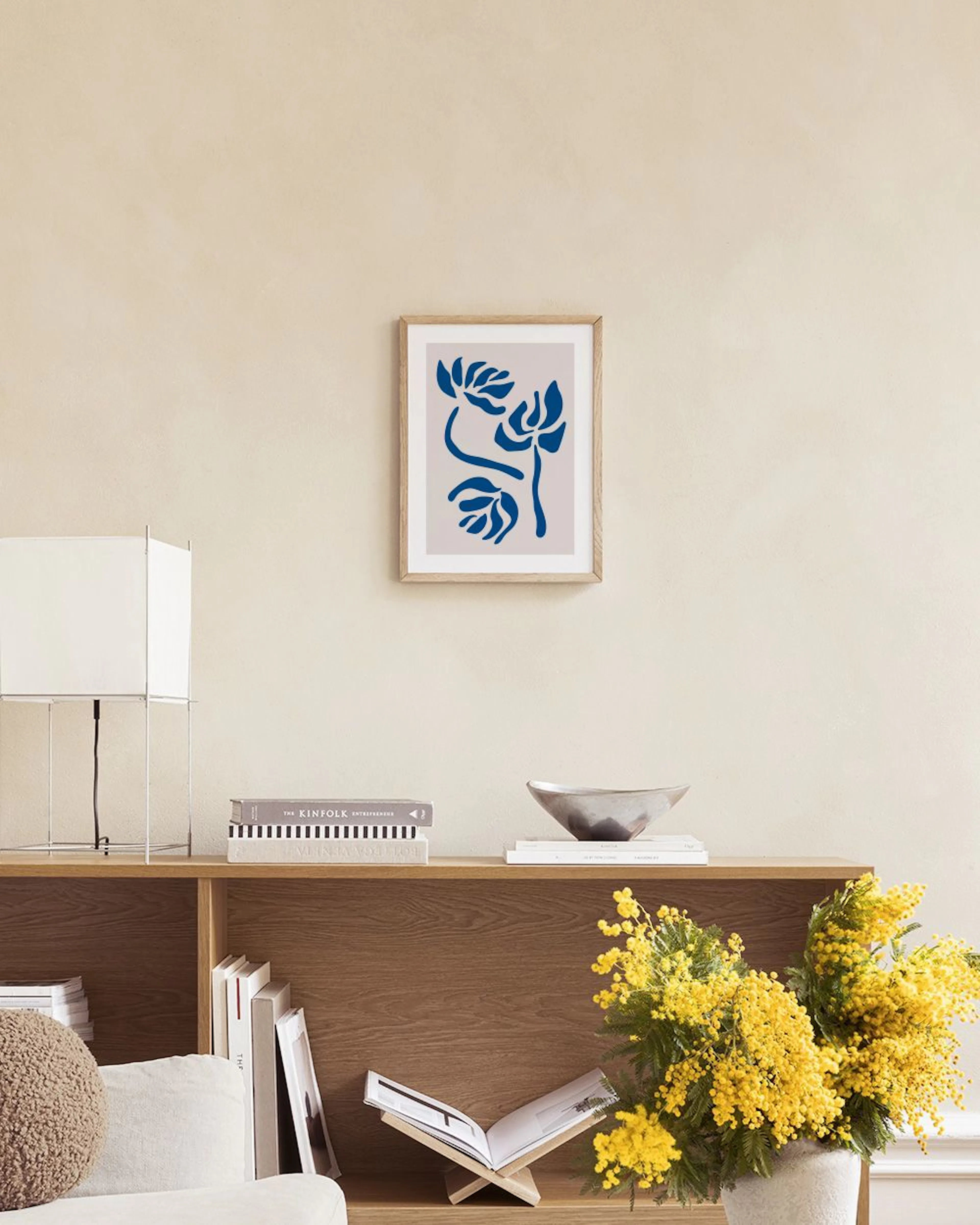 Abstract botanical print with deep blue stylized flowers on a beige background, displayed in a bright living room.