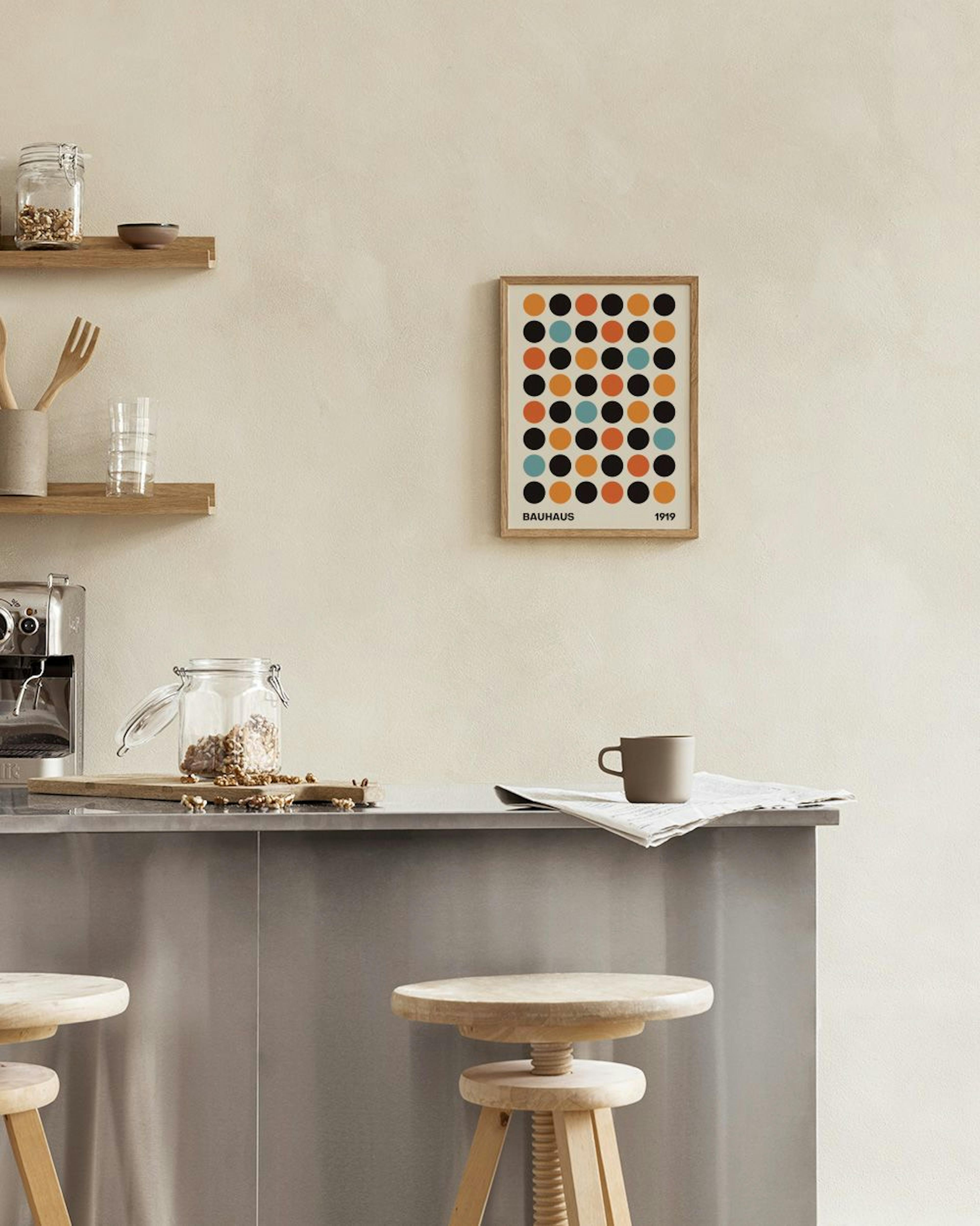 En Bauhaus plakat med sorte, orange og lyseblå prikker hængende over en grøn lænestol i en stue.